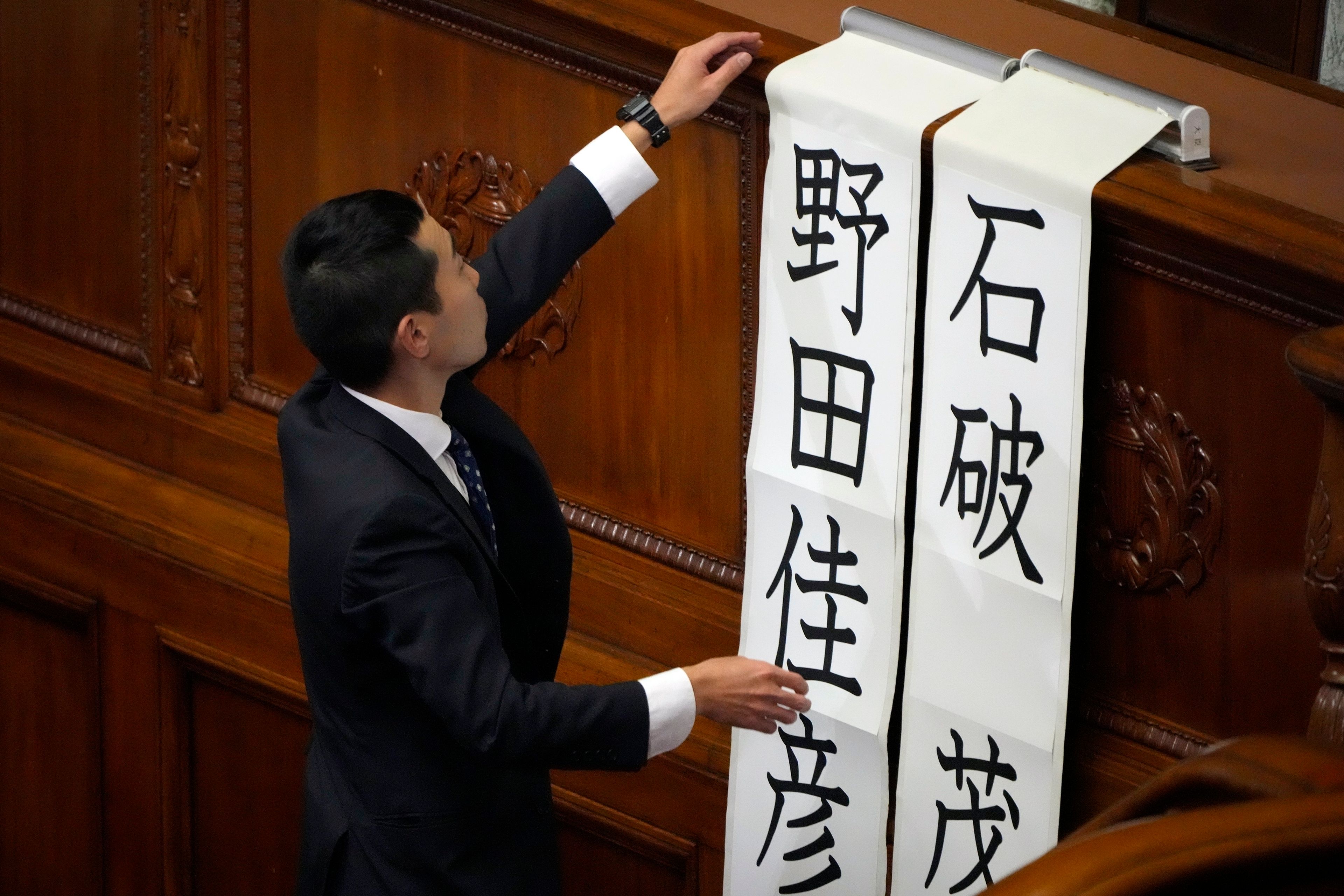 A staff member at parliament puts up two names, Shigeru Ishiba (of Japanese Prime Minister), right, and Yoshihiko Noda (leader of the Constitutional Democratic Party) for a runoff vote for a new prime minister at a special parliamentary session of the lower house Monday, Nov. 11, 2024, in Tokyo. (AP Photo/Eugene Hoshiko)