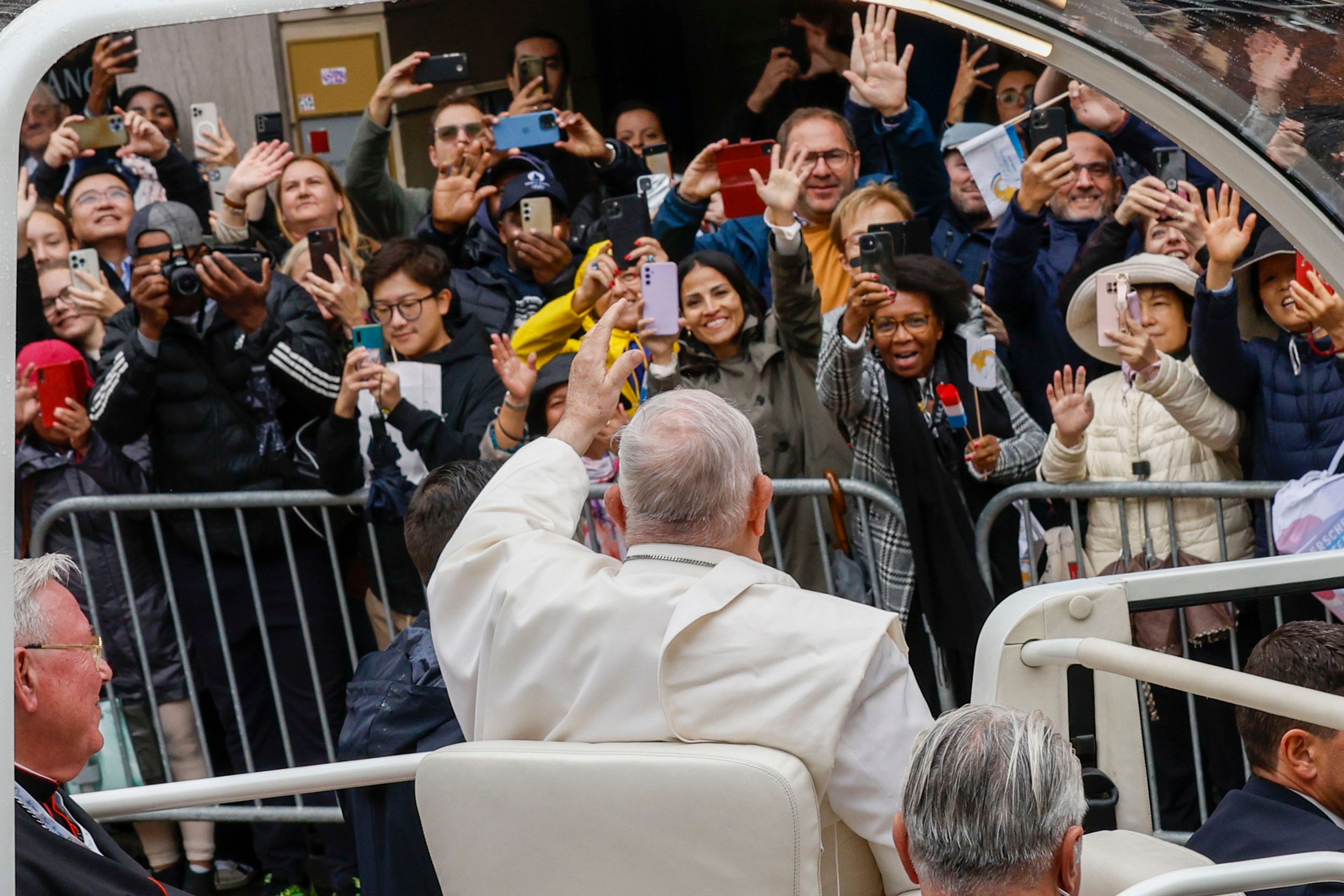 Pope Francis waves at a cheering crowd as he leaves with Archbishop of Luxembourg, Cardinal Jean-Claude Hollerich, left, in a popemobile the Cercle-Cite convention center in Luxembourg after a meeting with the national authorities and the civil society on the first day of Francis's four-day visit to Luxembourg and Belgium, Thursday, Sept. 26, 2024. (AP Photo/Omar Havana)