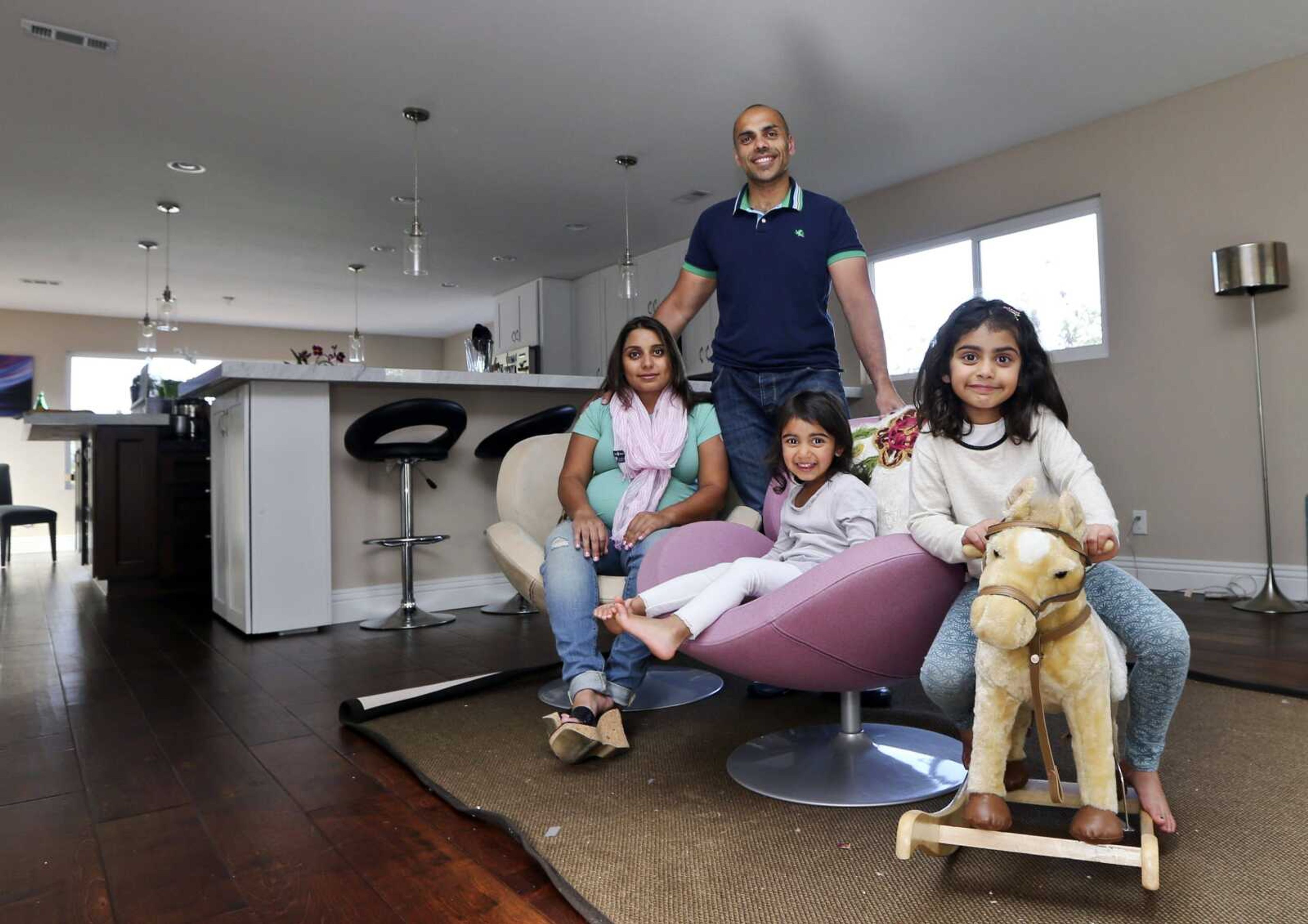 The Jaswal family, with Imran, standing, his wife Aniqa, left, and daughters, Arissa, right, and Jayda, pose for photos in the family room at their home April 16 in La Jolla, Calif. The couple bought the four-bedroom house about 10 minutes from the beach in February. Once Imran&#8217;s management consulting business began flourishing, the couple felt comfortable enough after years of renting to buy their first home. (Lenny Ignelzi ~ Associated Press)