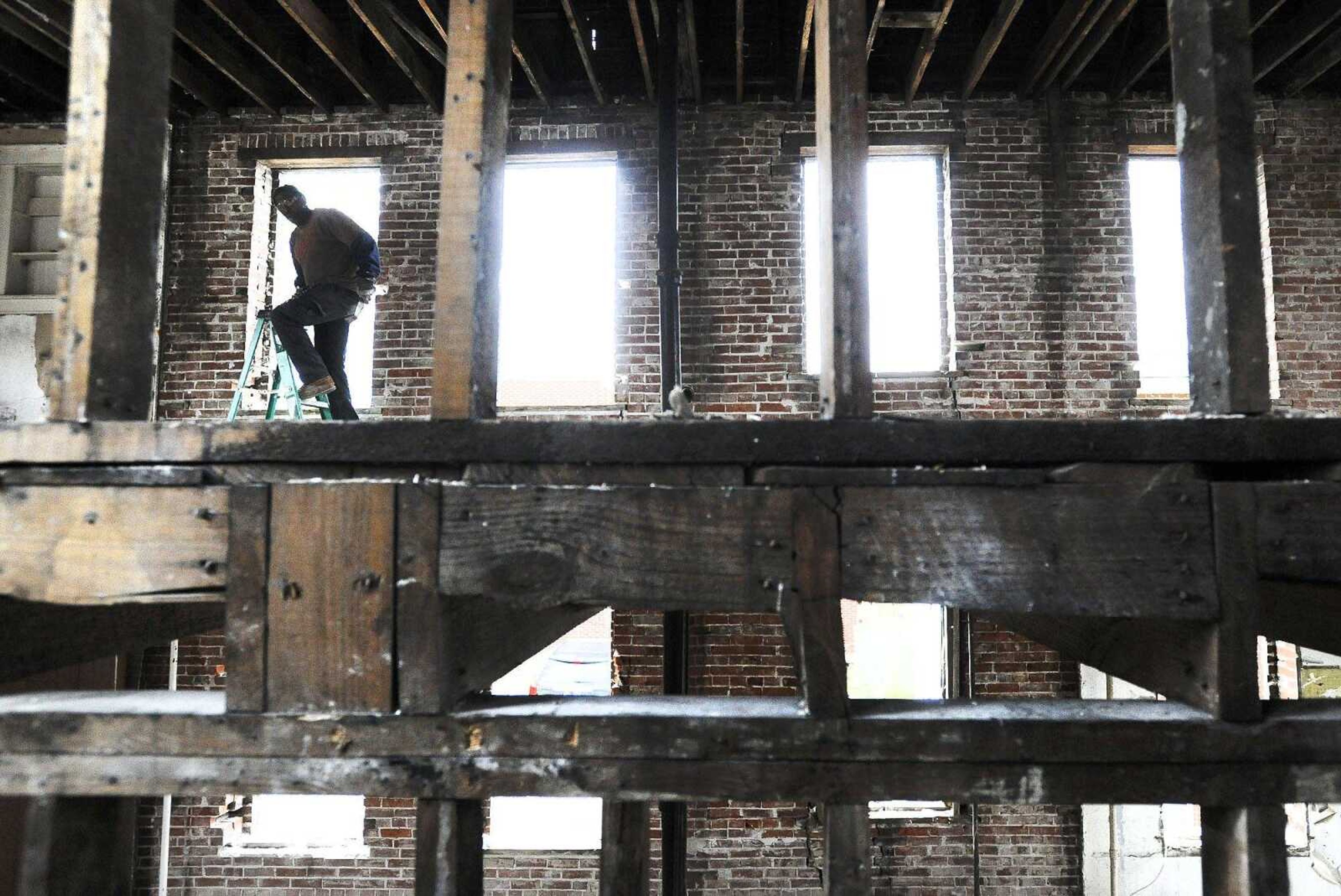 Emerald Henry removes nails from joist beams on the second floor of the Lorimier Apartments on Wednesday morning in Cape Girardeau. The apartment building, listed on the National Register of Historic Places and the city's Endangered Buildings List, is being brought back to life by Centurion Development LLC.