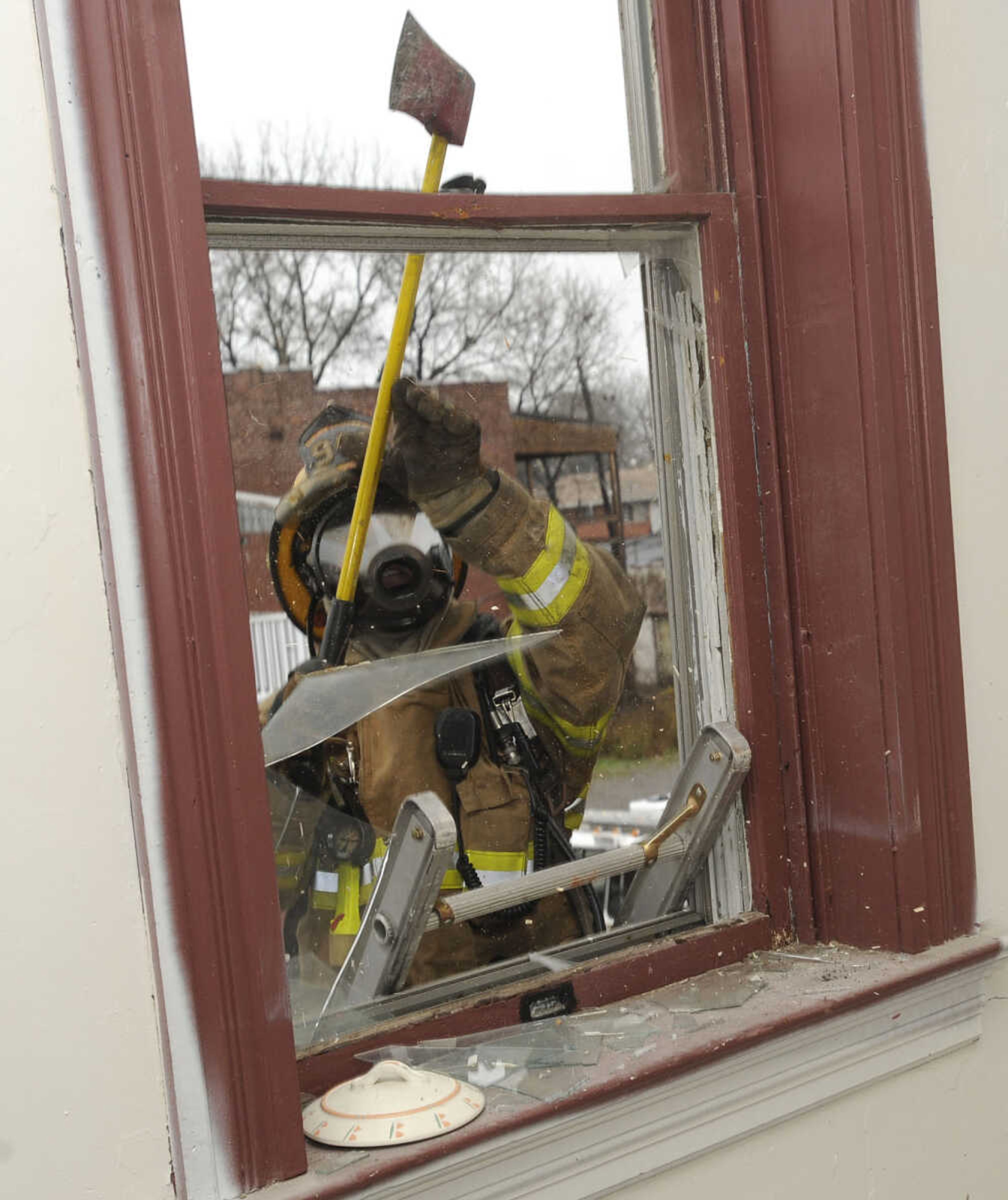 Firefighter Sam Jenne breaks out a second-floor window.