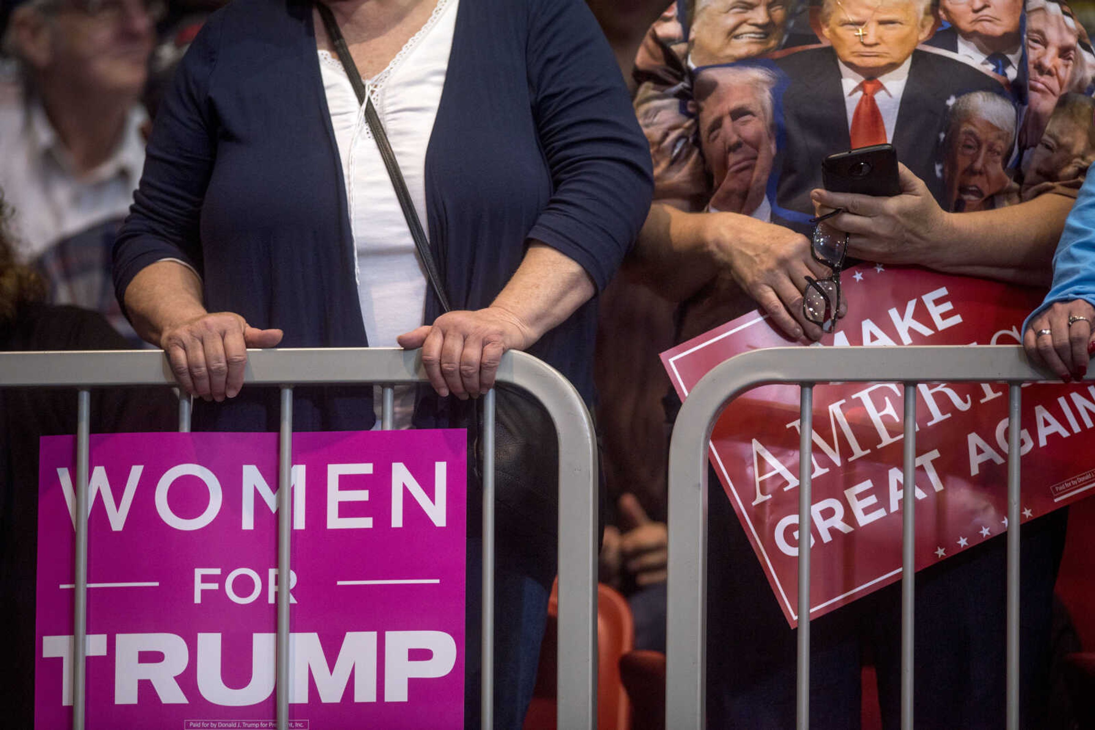 Members of the crowd hold signs at the Show Me Center during a rally for President Trump Monday.