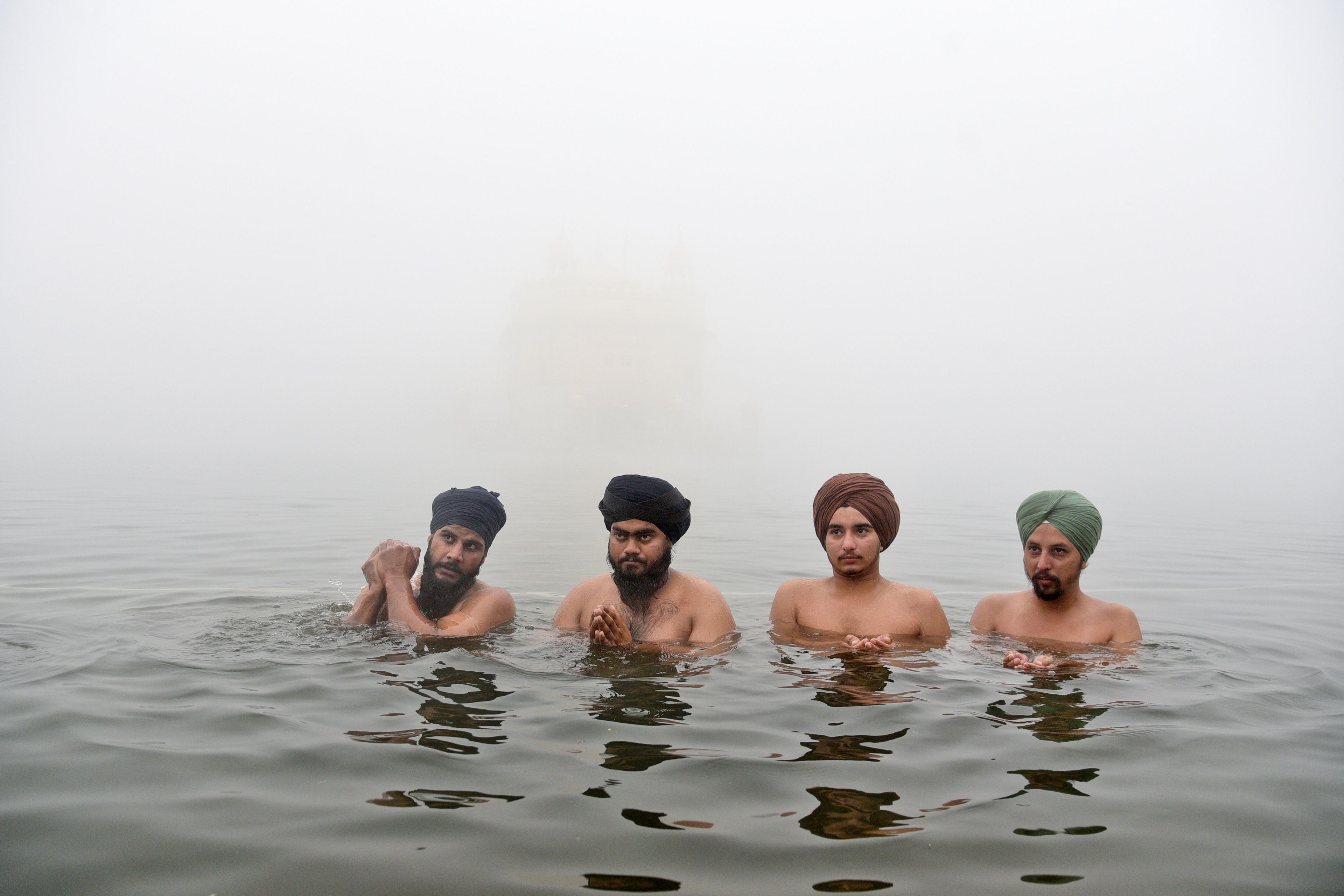 Sikh devotees pray while standing in the pond surrounding the Golden Temple as they celebrate the birth anniversary of the first Sikh guru, Guru Nanak, in Amritsar, India, Friday, Nov. 15, 2024. (AP Photo/Prabhjot Gill)