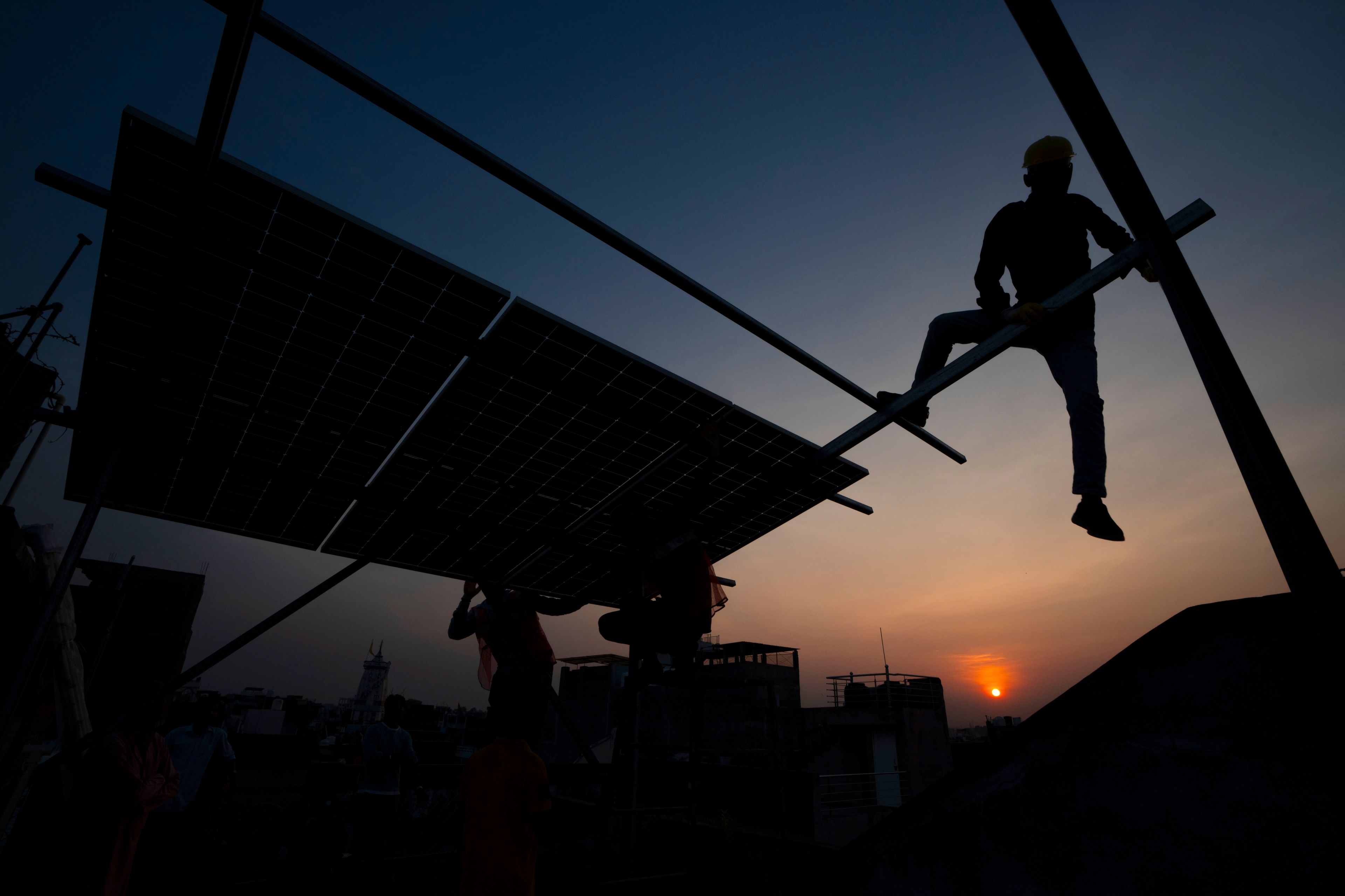 FILE - Workers install rooftop solar panels on a house in Prayagraj, India, Oct. 14, 2024. (AP Photo/Rajesh Kumar Singh, File)