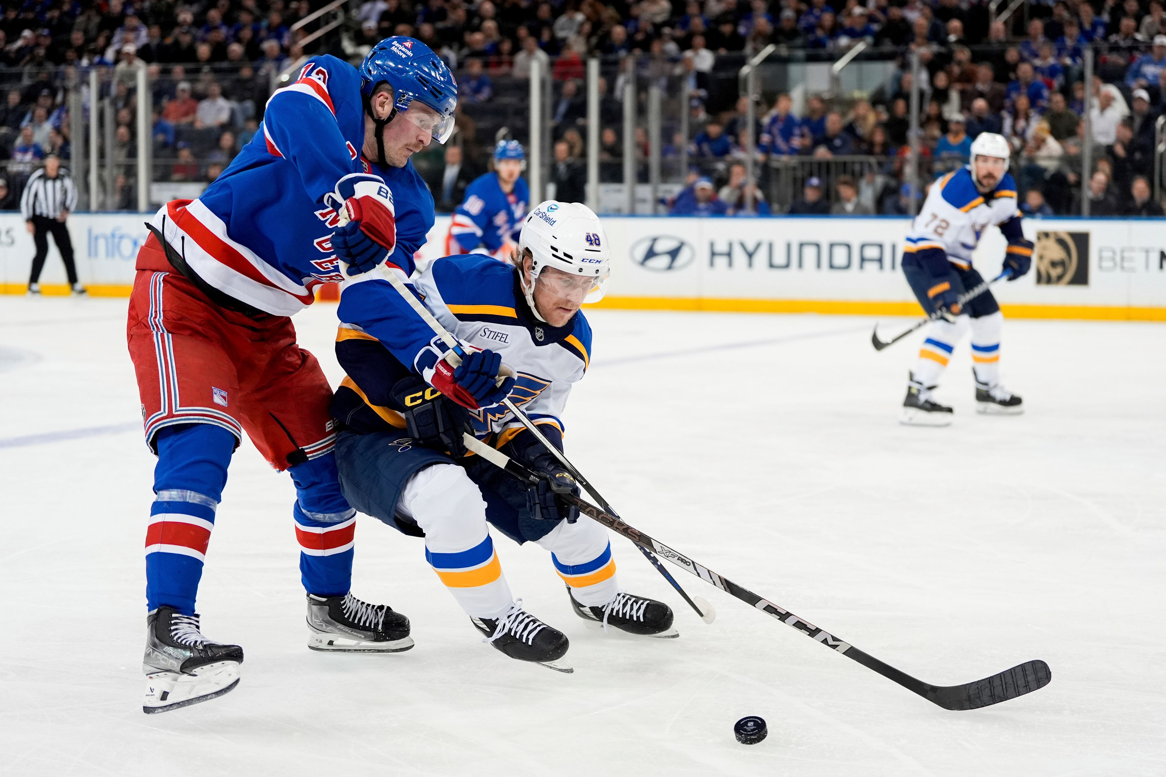 New York Rangers left wing Alexis Lafrenière (13) and St. Louis Blues defenseman Scott Perunovich (48) fight for the puck during the first period of an NHL hockey game, Monday, Nov. 25, 2024, in New York. (AP Photo/Julia Demaree Nikhinson)