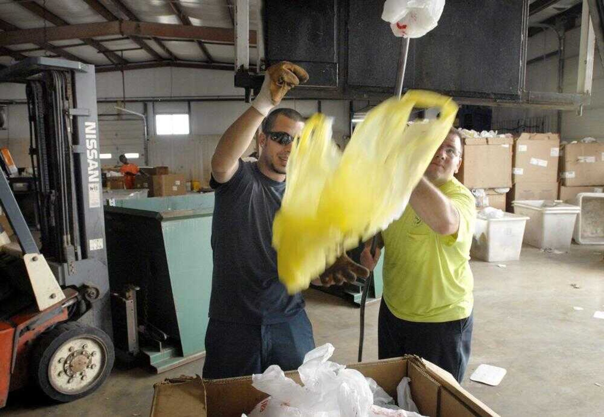 Justin Jones, left, and Jeff Garland pulled the last plastic bags out of a curbside recycling truck Friday at the Cape Girar-deau Recycling Center. Sales of recyclables covers only 7 percent of the needed budget for the recycling program. (Kit Doyle)