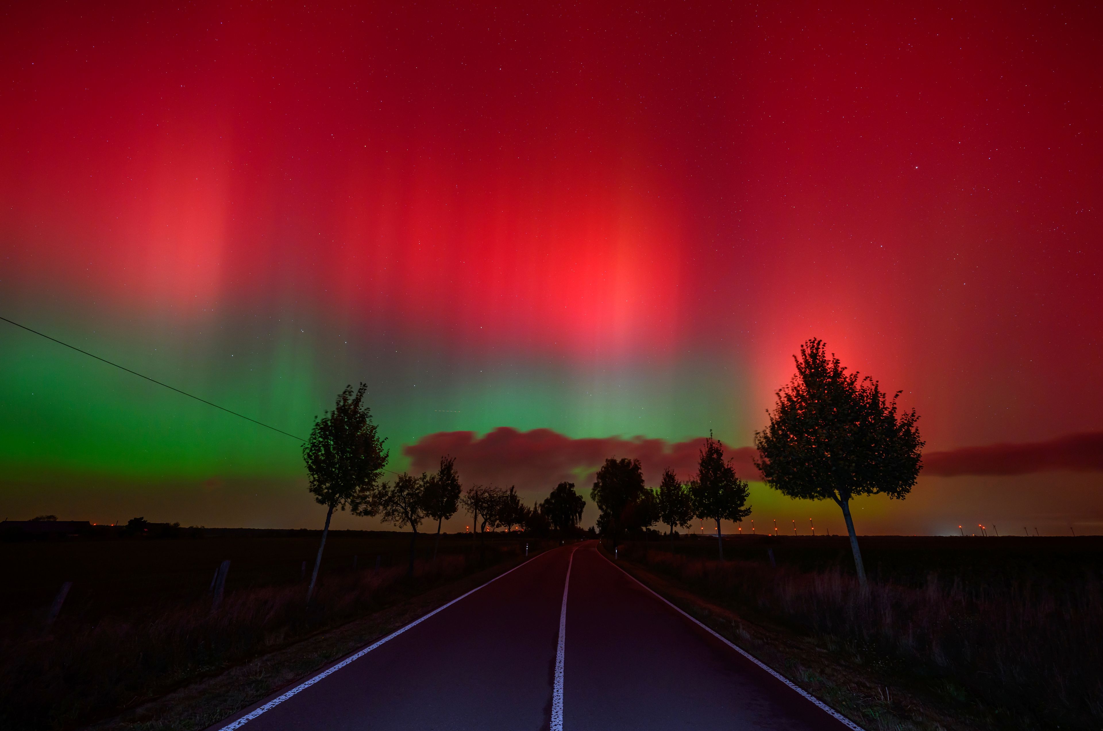 The Northern lights glow in the night sky above a road in Lietzen, eastern Germany. (Patrick Pleul/dpa via AP)