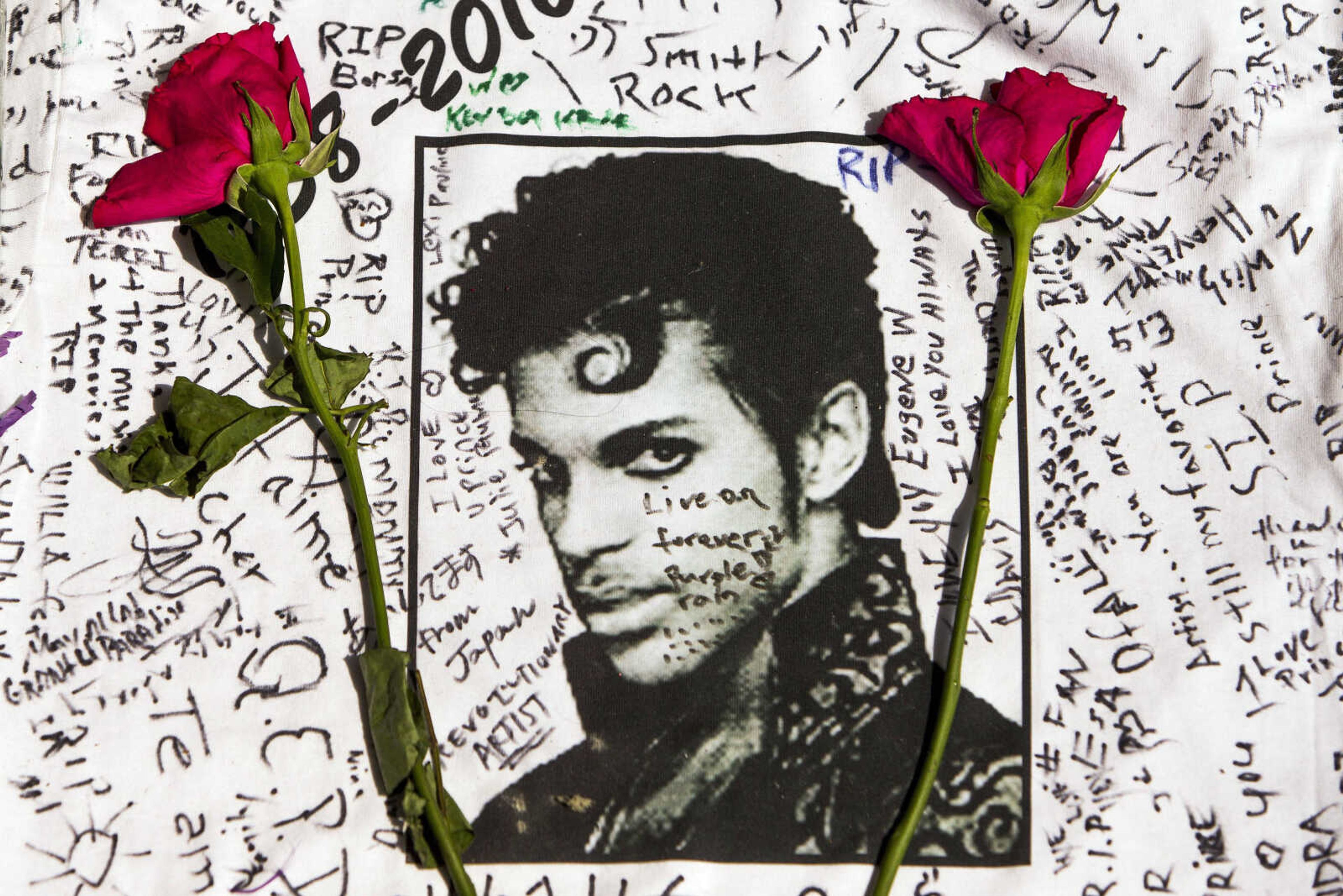 Flowers lie on a T-shirt signed by fans at a makeshift memorial for musician Prince on April 22 outside the Apollo Theater in New York. The singer died April 21 at the age of 57.