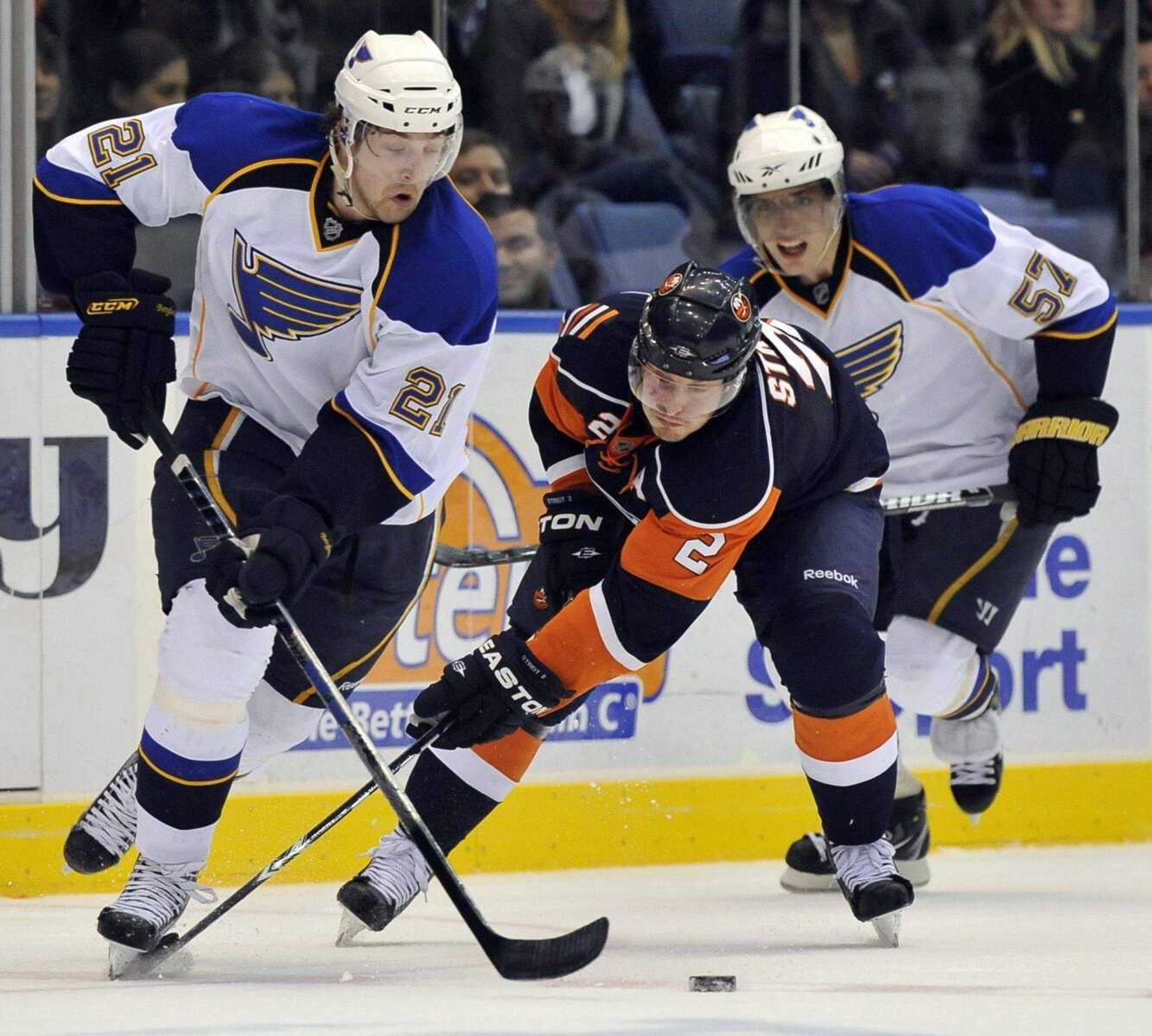 St. Louis Blues' Patrik Berglund (21), who scored the first Blues' goal, keeps the puck away from New York Islanders' Mark Streit (2) as Blues' David Perron (57) defends from behind during the third period of an NHL hockey game Thursday, March 11, 2010, in Uniondale, N.Y. The Blues won 2-1 in a shootout. (AP Photo/Kathy Kmonicek)