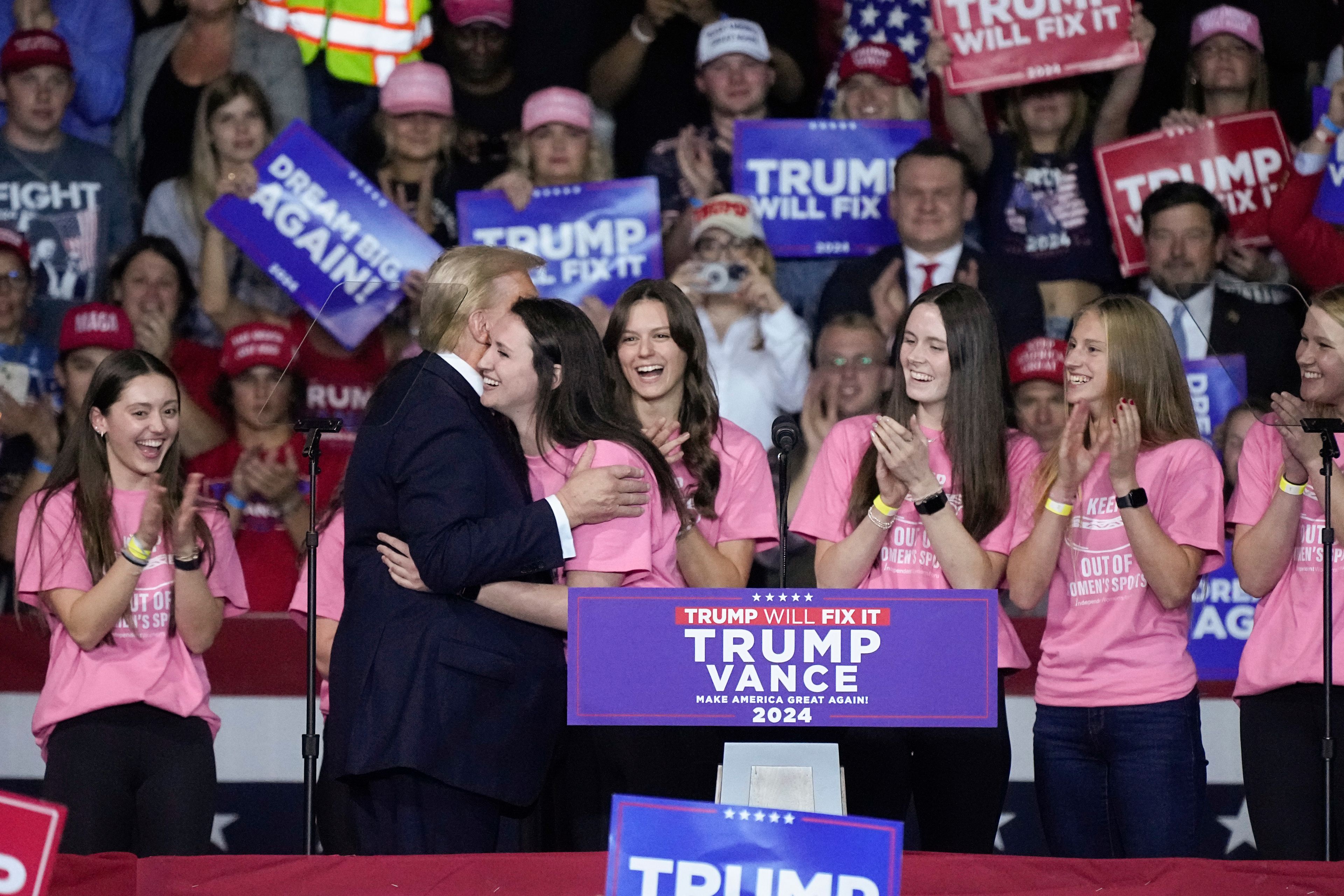 Lilly Mullens of the Roanoke College Swim Team, is hugged by Republican presidential nominee former President Donald Trump, at a campaign rally, Saturday Nov. 2, 2024, in Salem, Va. (AP Photo/Steve Helber)