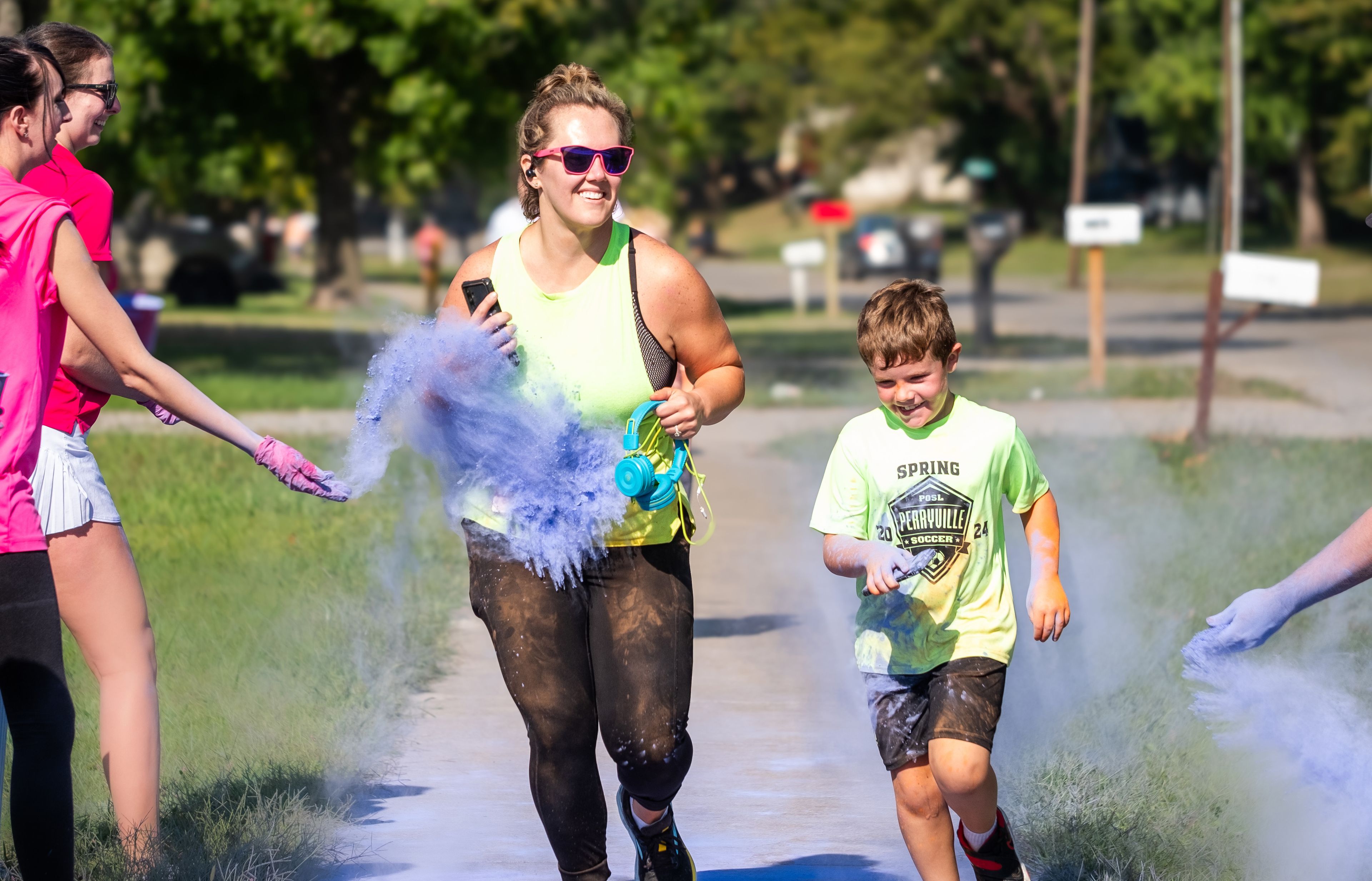 Savannah Martin and Jackson Martin of Perryville share laughter as they run through a cloud of vibrant chalk. 
