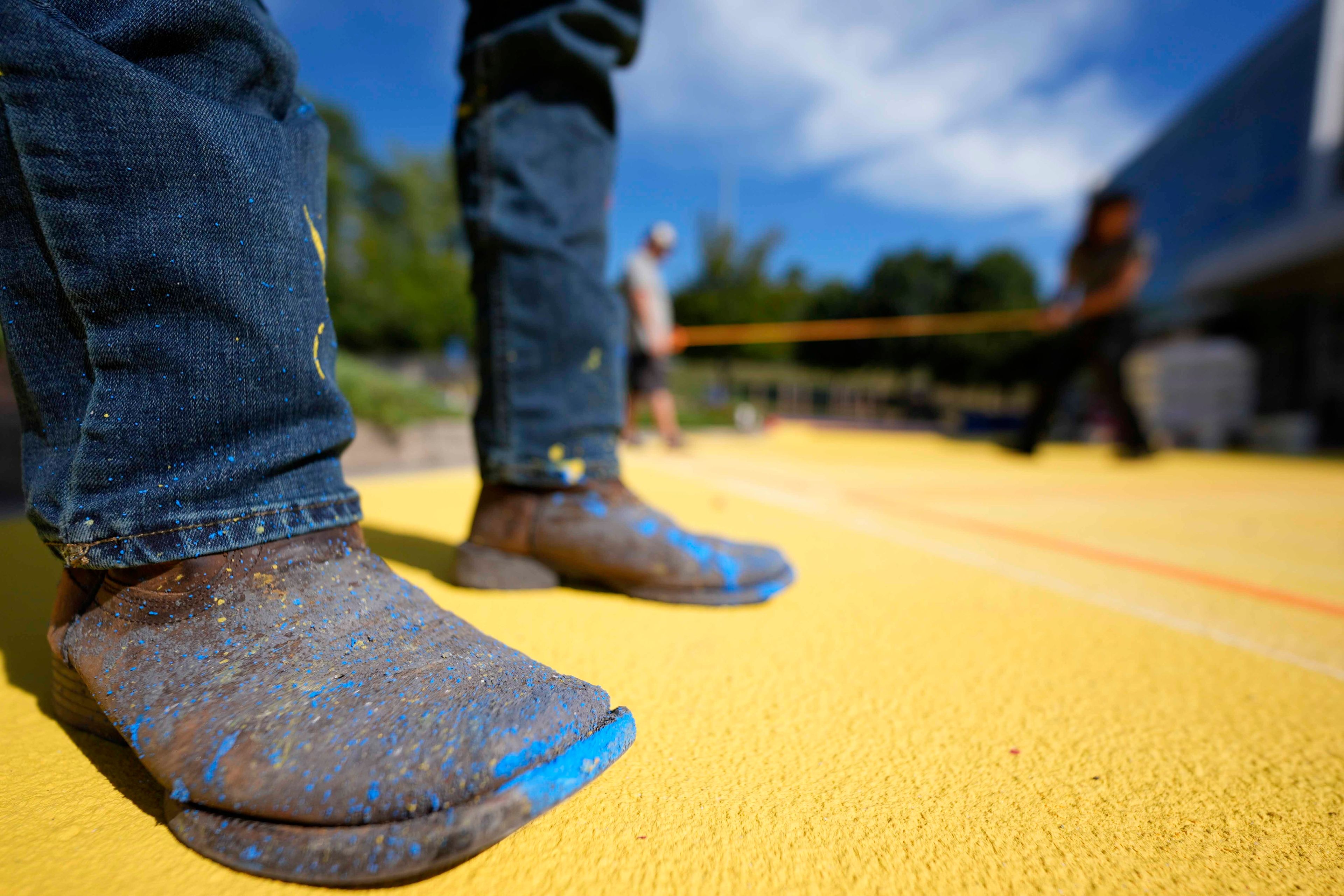 Ronnie Jefferies works on the parking lot at Science, Arts and Entrepreneurship School where it is being repainted to help cool it by making it more reflective, Wednesday, Sept. 4, 2024, in Mableton, Ga. (AP Photo/Mike Stewart)