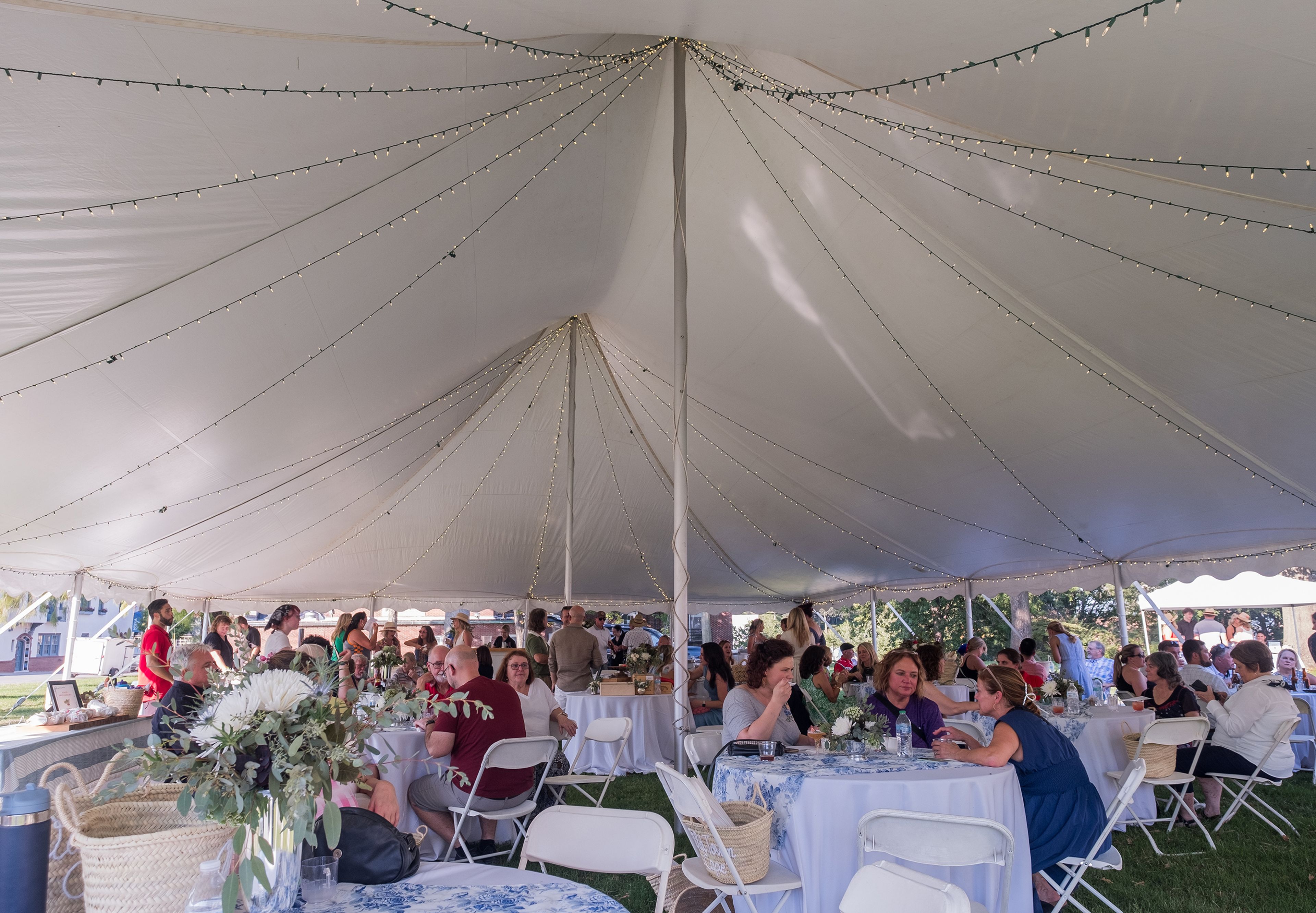 Guests gather under a large awning, enjoying the shade as they mingle.