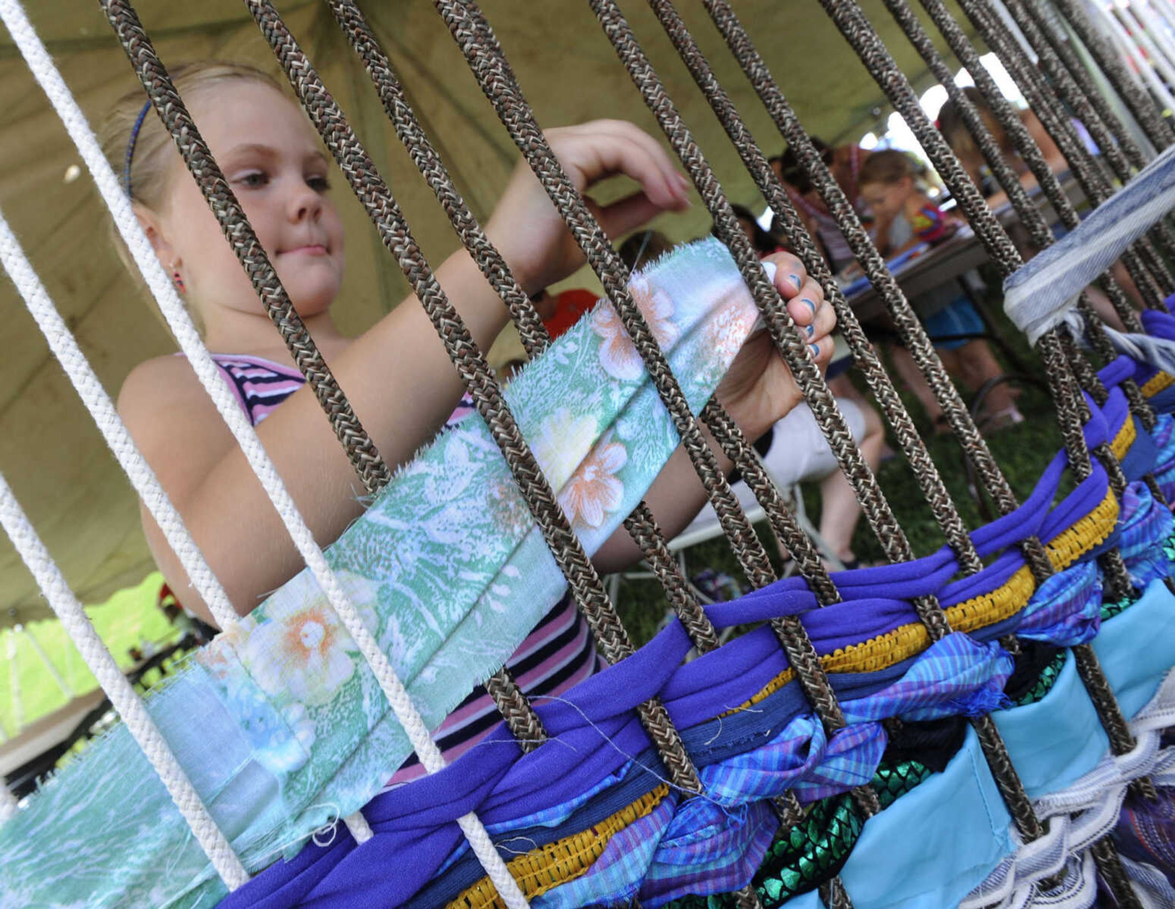 FRED LYNCH ~ flynch@semissourian.com
Morgan Nickell adds a splash of color to the collaborative weaving Saturday, June 21, 2014 in the art tent at the River Campus Summer Arts Festival in Cape Girardeau.