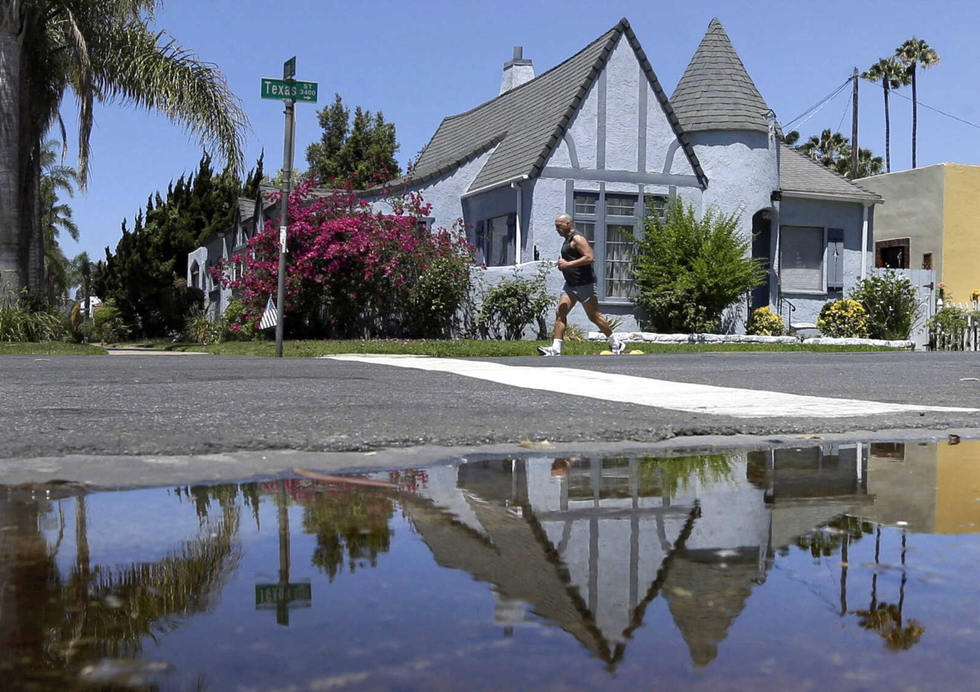 A house is reflected in a puddle of water from an irrigated front yard July 9 in San Diego. (Associated Press file)