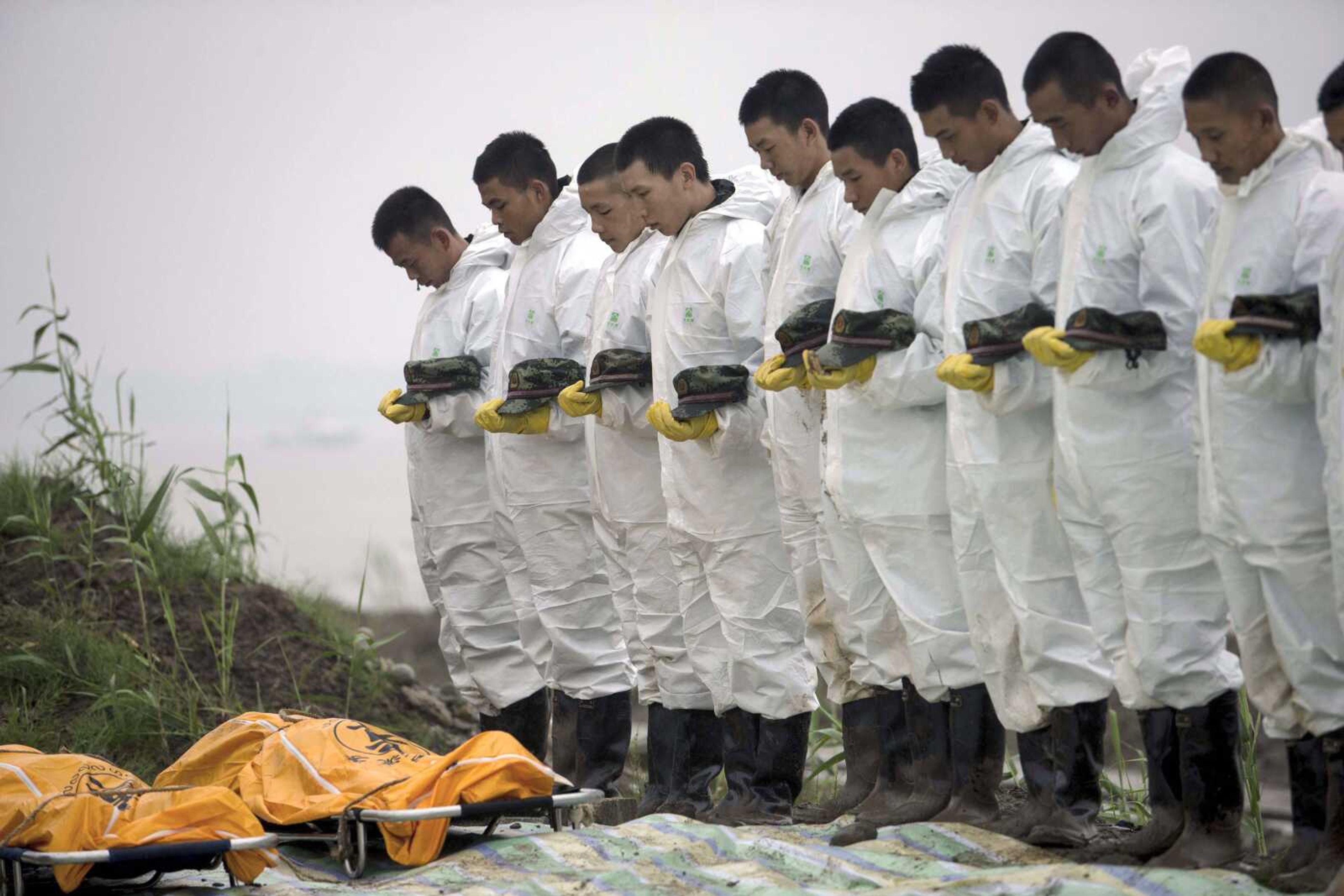 Rescuers observe a moment of silence for victims recovered Wednesday from the capsized tourist ship in the Yangtze River in China's Hubei province. (Chinatopix)