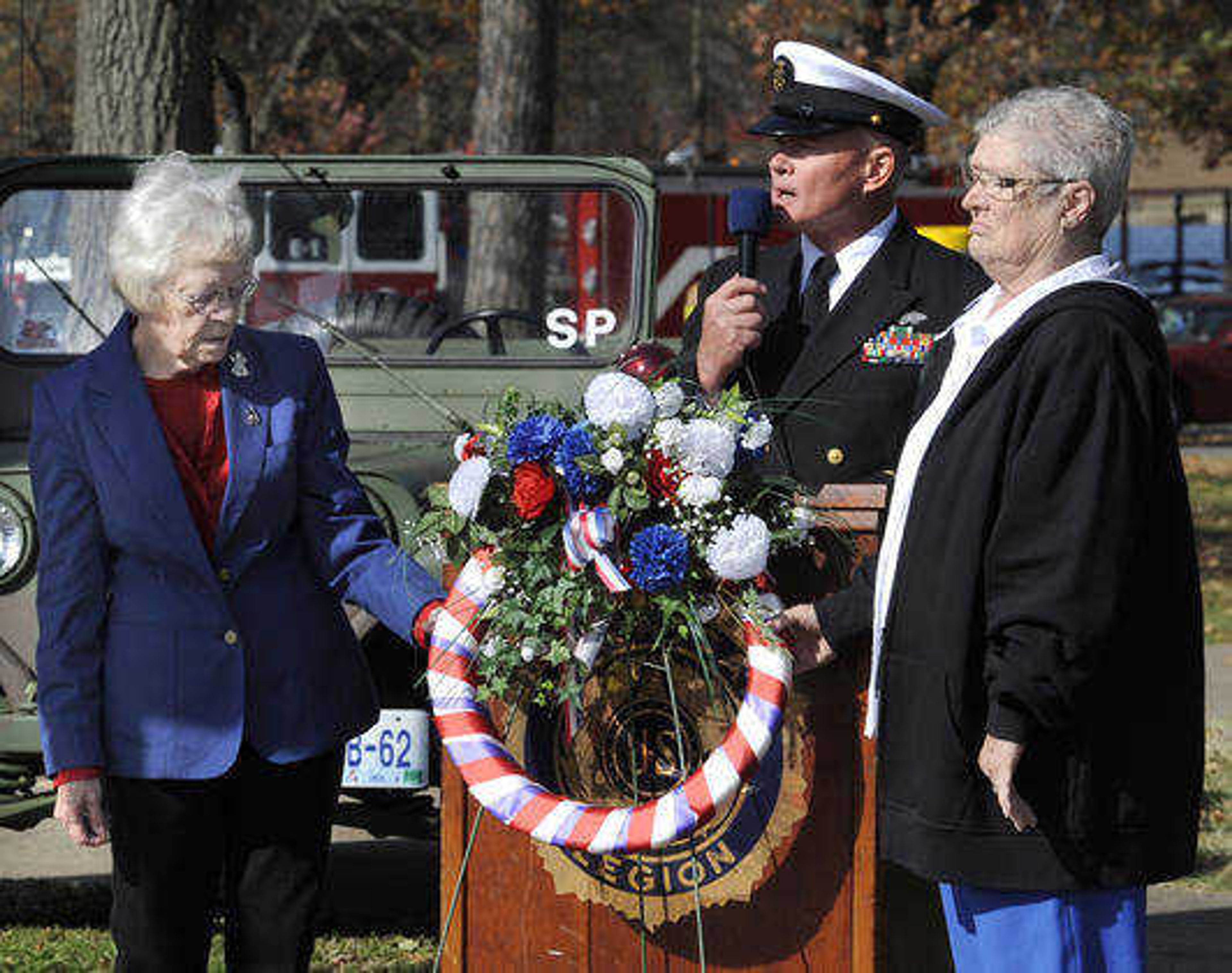 Retha Popp, left, and Judy Biester with the VFW Post 3838 Ladies Auxiliary present a wreath with U.S. Navy Retired Master Chief Petty Officer Mike Morgan at the Veterans Day ceremony Friday, Nov. 11, 2011 at Freedom Corner. (Fred Lynch)