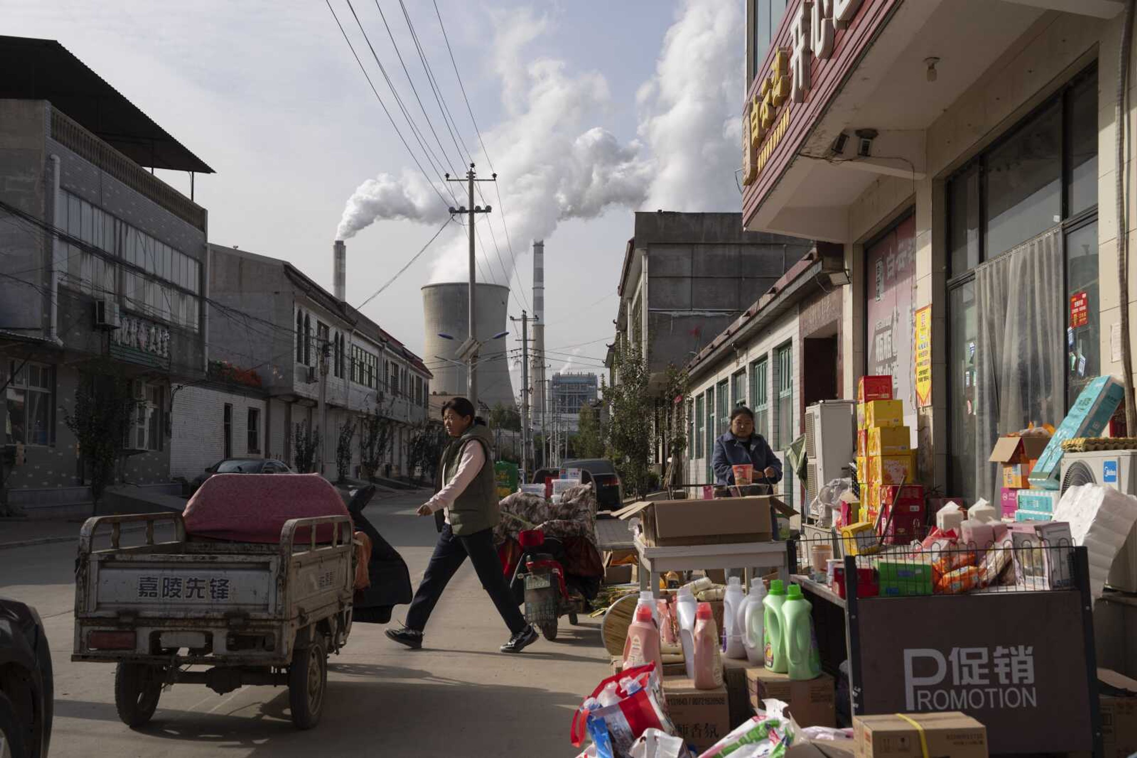 Guohua Power Station, a coal-fired power plant, operates as people sell items on a street Nov. 10 in Dingzhou, Baoding, in the northern China's Hebei province.