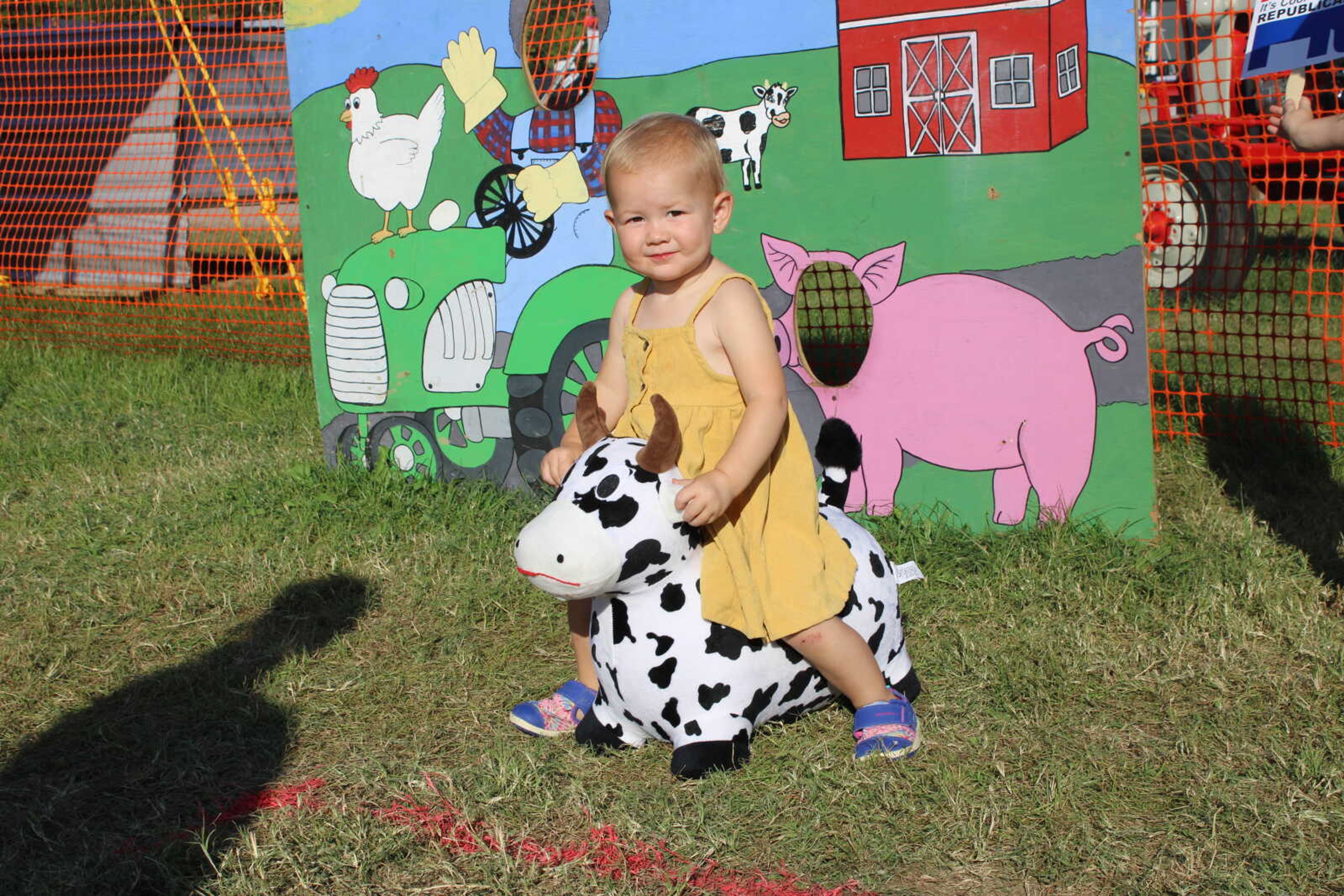 Lydia Mueller rides a toy bull in the kids area.