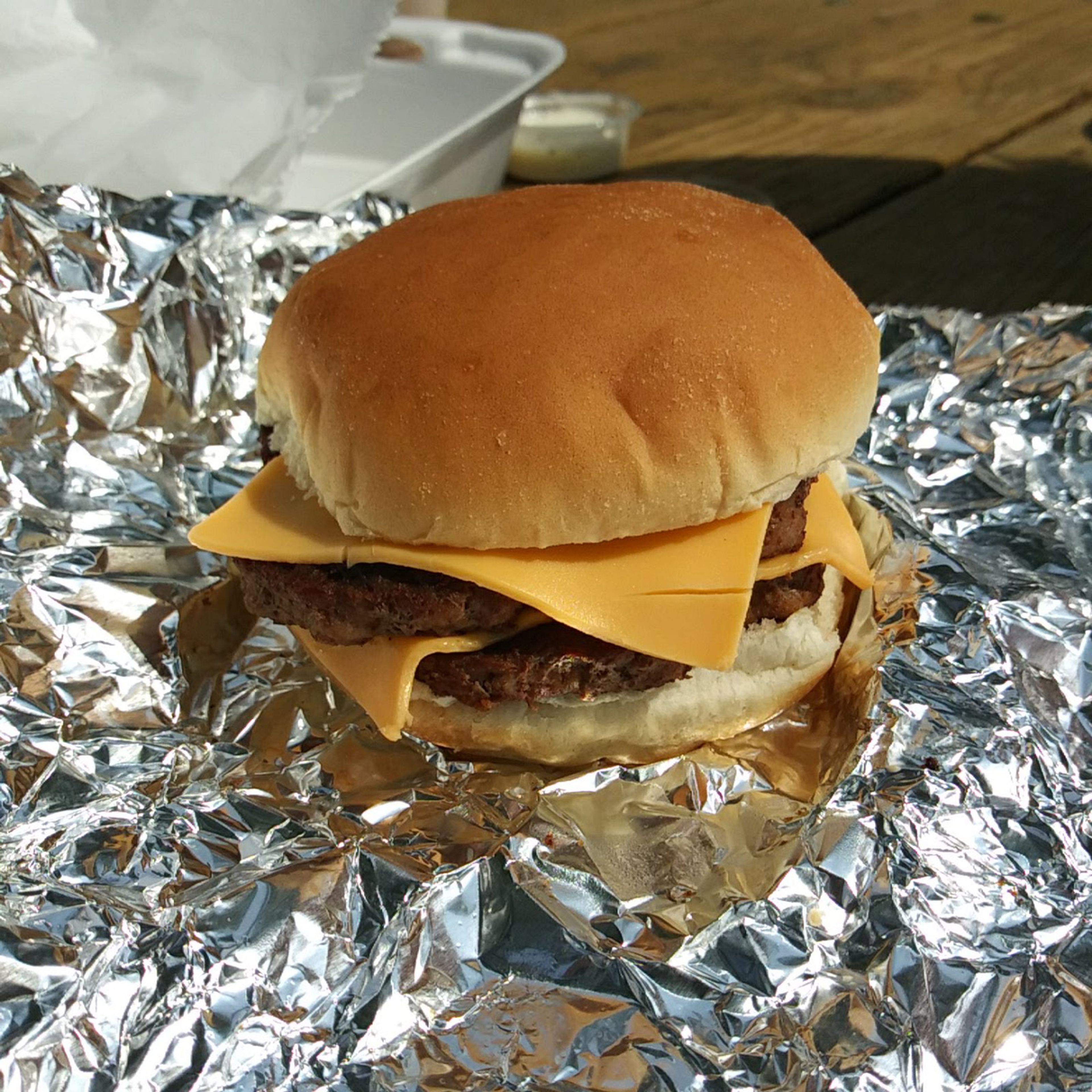 A Uniquely Perfect double cheeseburger, cooked fresh, unwrapped, and consumed immediately.