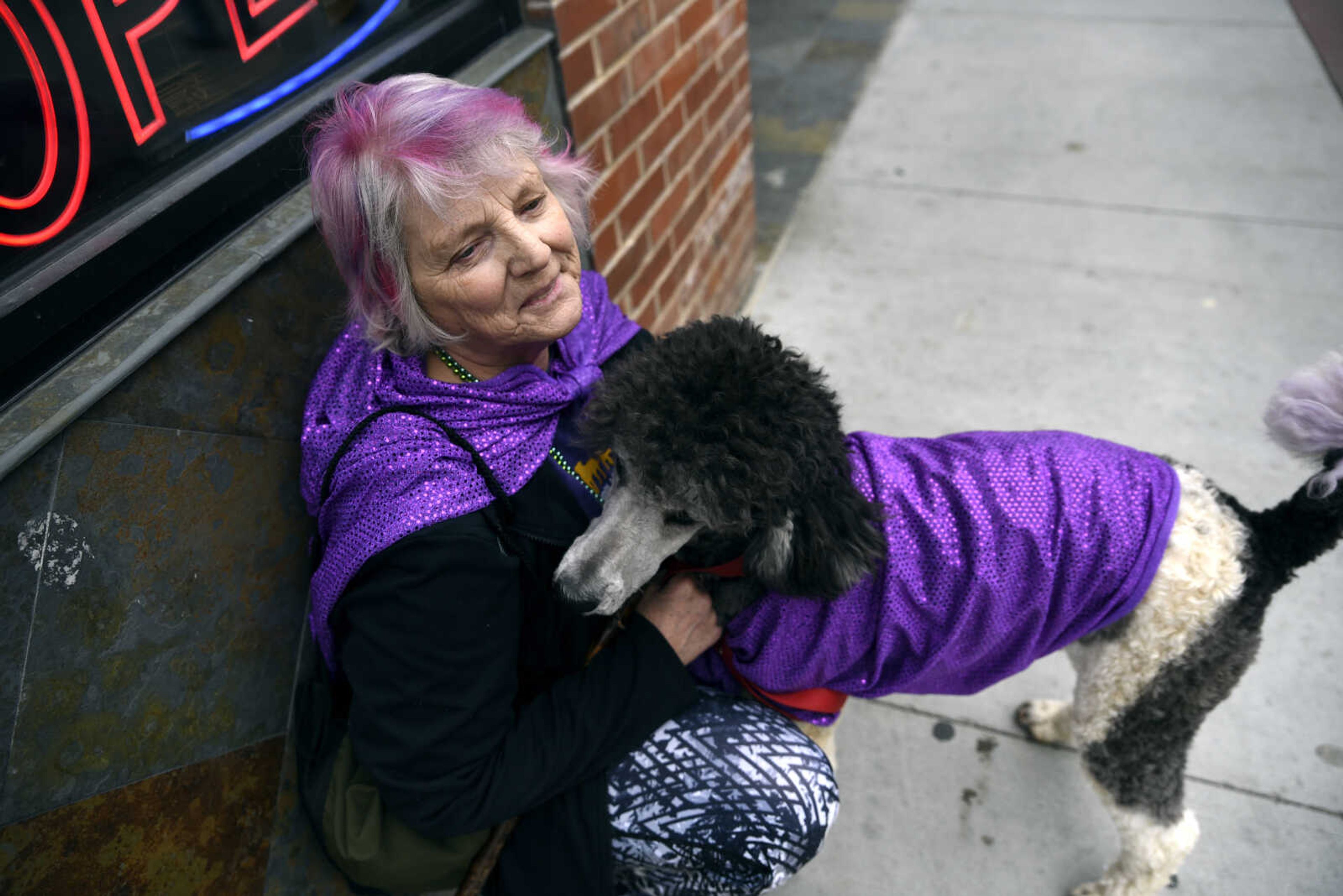 Pam Wiles sits on the sidewalk with her 10-month-old standard poodle Balboa while watching the 2nd Annual Mardi Paws Parade of Pets hosted by Mississippi Mutts on Sunday, March 18, 2018, in downtown Cape Girardeau.