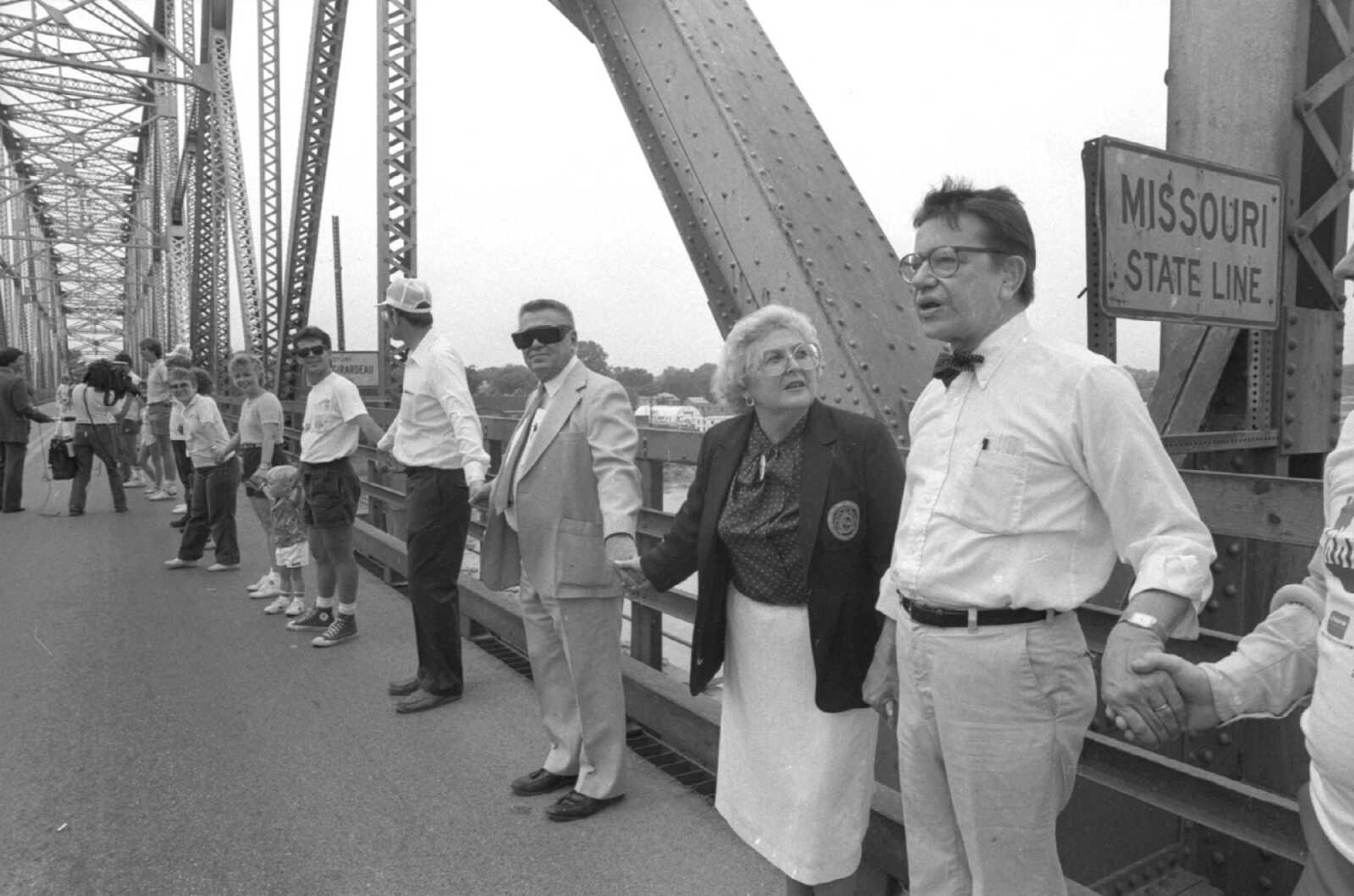 Published 25 May 1986, pg. 1
Missouri and Illinois were linked on the Mississippi River bridge Sunday as a part of "Hands Across America" activities. Here, Illinois Sen. Paul Simon, right, joins hands with Missouri State Rep. Mary Kasten at the Missouri-Illinois line on the bridge. Standing next to Mrs. Kasten is her husband, Dr. Melvin Kasten. (Missourian archive photo by Fred Lynch)