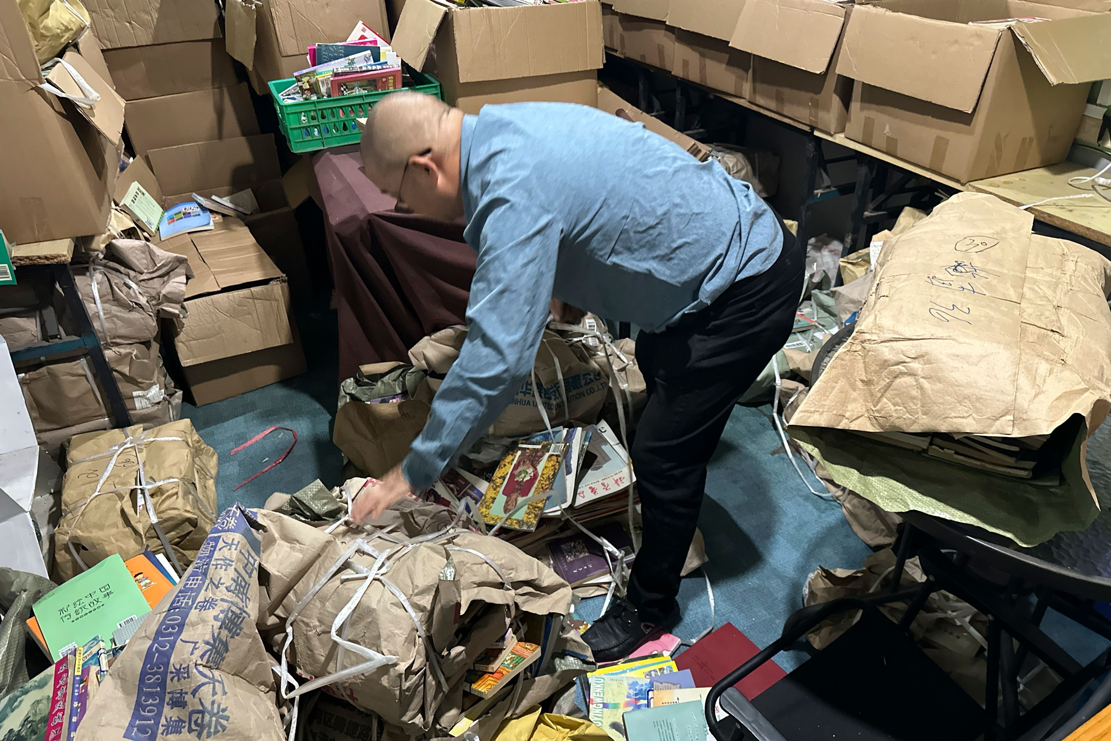 Secondhand bookstore owner Wang Yingxing bundles books at a storage shed near his shuttered shop in Ningbo, in eastern China's Zhejiang province, Oct. 9, 2024. (AP Photo/Dake Kang)