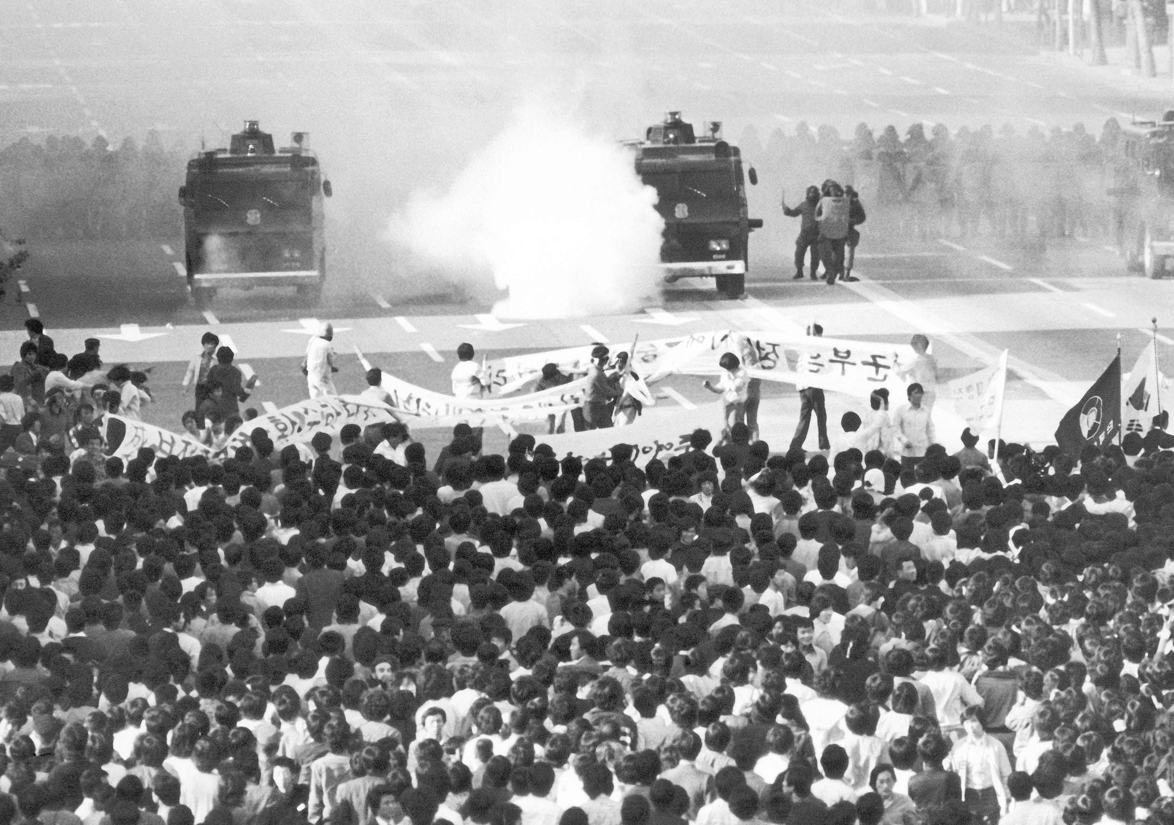 FILE- Police vehicle sprays tear gas at tens of thousands of student demonstrators in downtown Seoul, South Korea on Thursday, May 15, 1980. (AP Photo/Kim Chon-Kil, File)