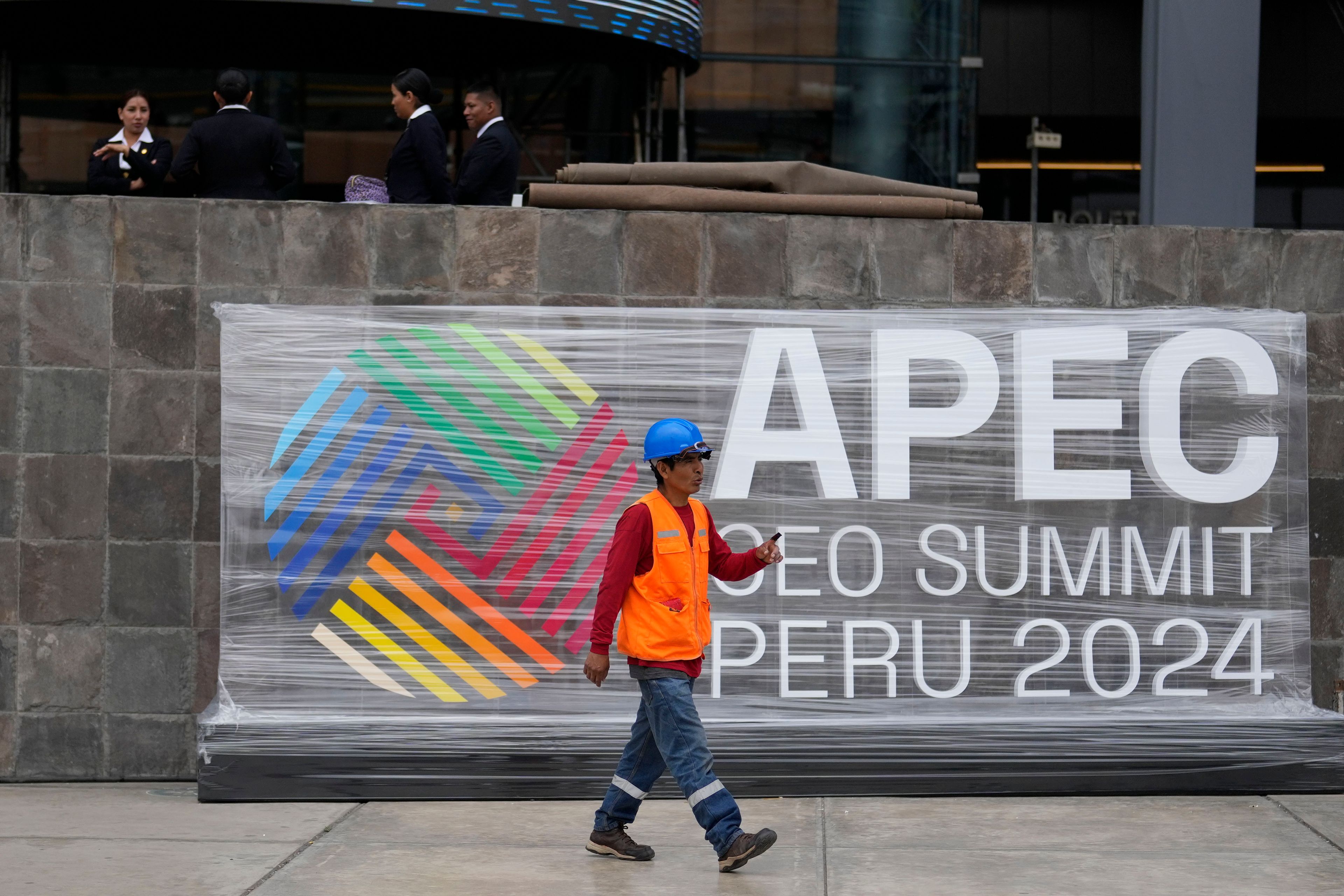 A worker walks past a sign presenting the Asia-Pacific Economic Cooperation (APEC) summit outside the Ministry of Culture in Lima, Peru, Tuesday, Nov. 12, 2024. (AP Photo/Fernando Vergara)