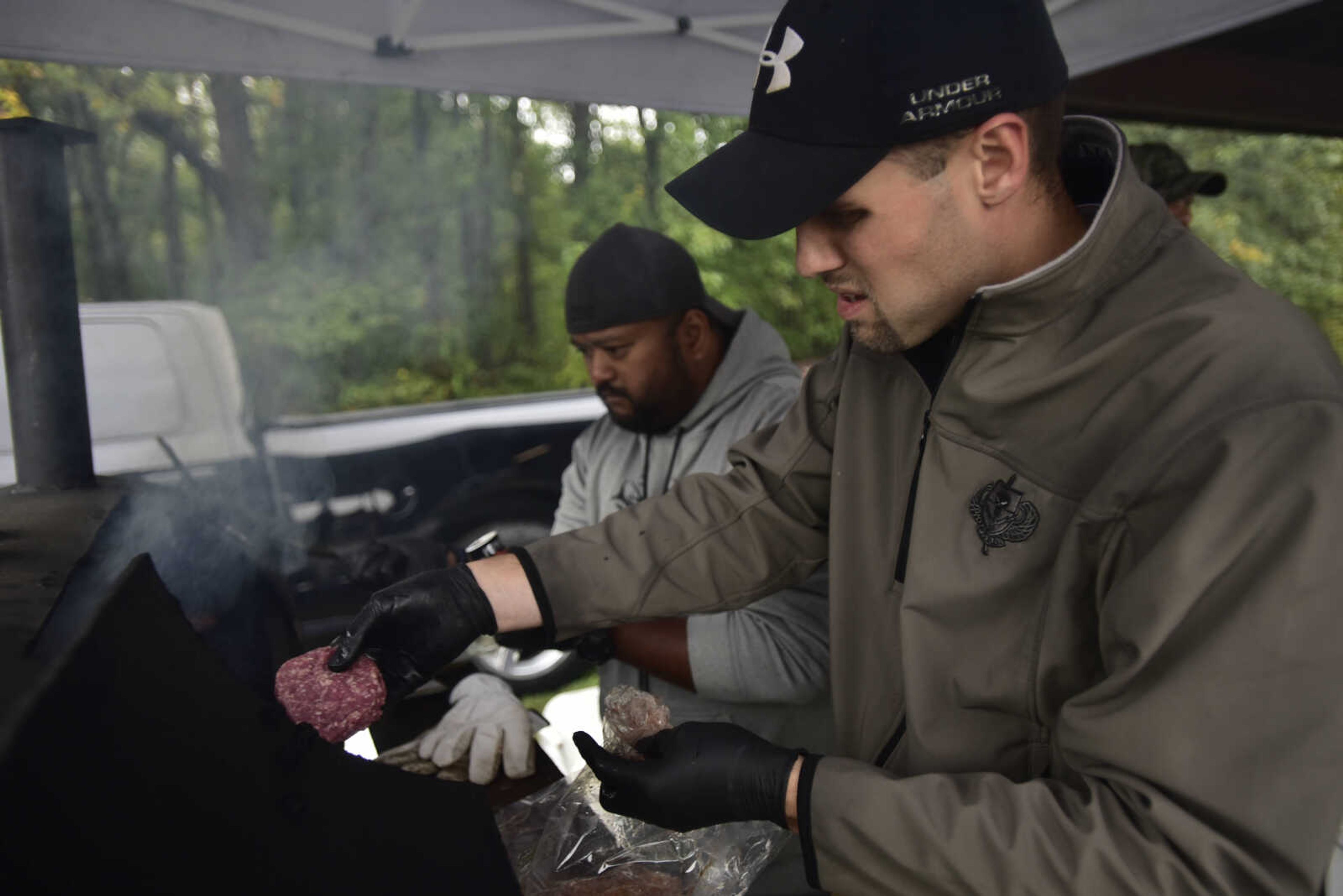 Cape Girardeau police officer Orrin Hawkins, right, throws a hamburger patty on the grill while his fellow officer Cary Dunavan seasons burgers at the inaugural Fishing Rodeo held Oct. 15, 2017 at Elks Lake in Cape Girardeau.