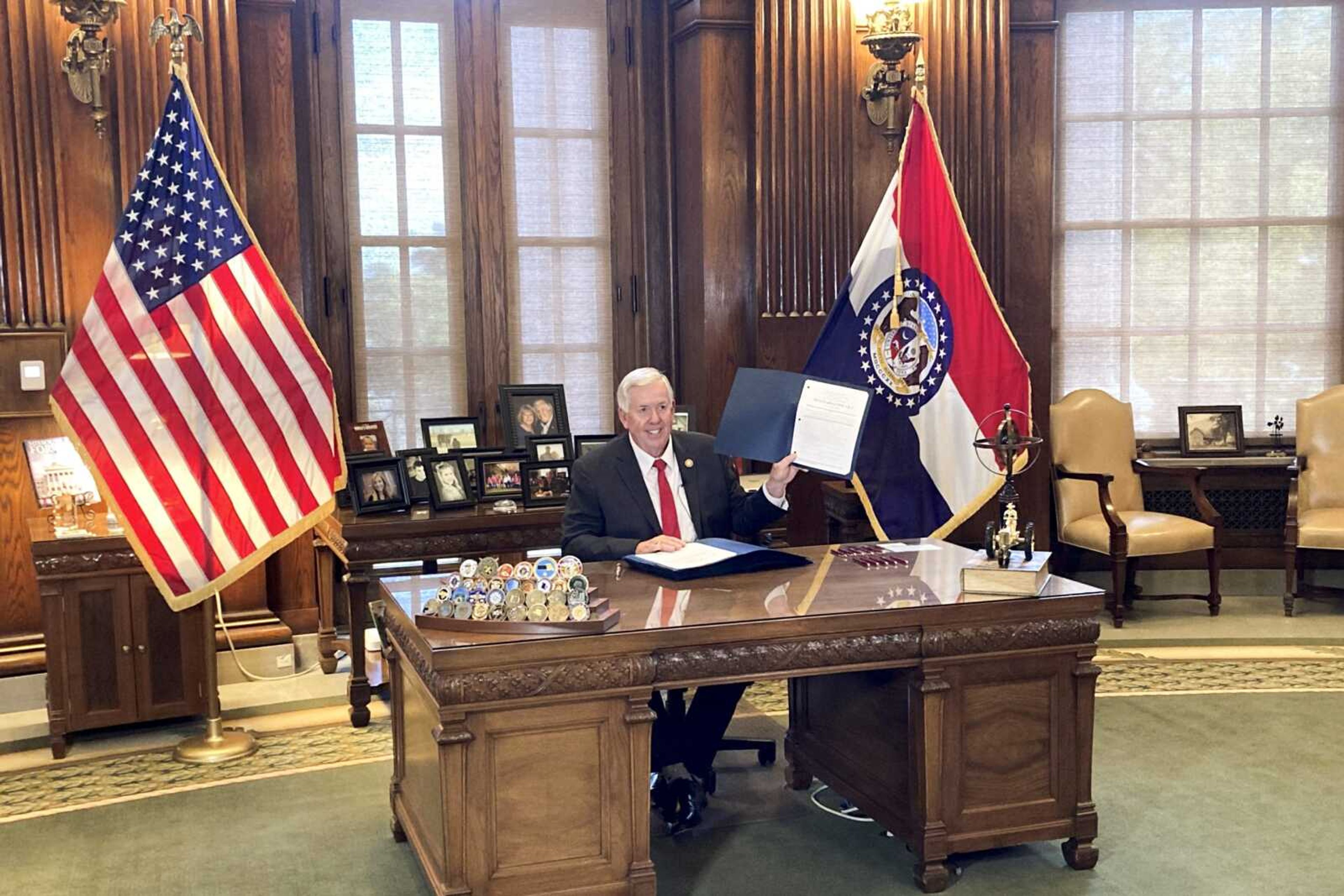 Gov. Mike Parson holds up legislation cutting the state's income tax rate after signing it into law Wednesday at his Capitol office in Jefferson City, Missouri. Parson said the new law would reduce people's taxes by 5% and cost the state about $760 million when fully phased in over several years.