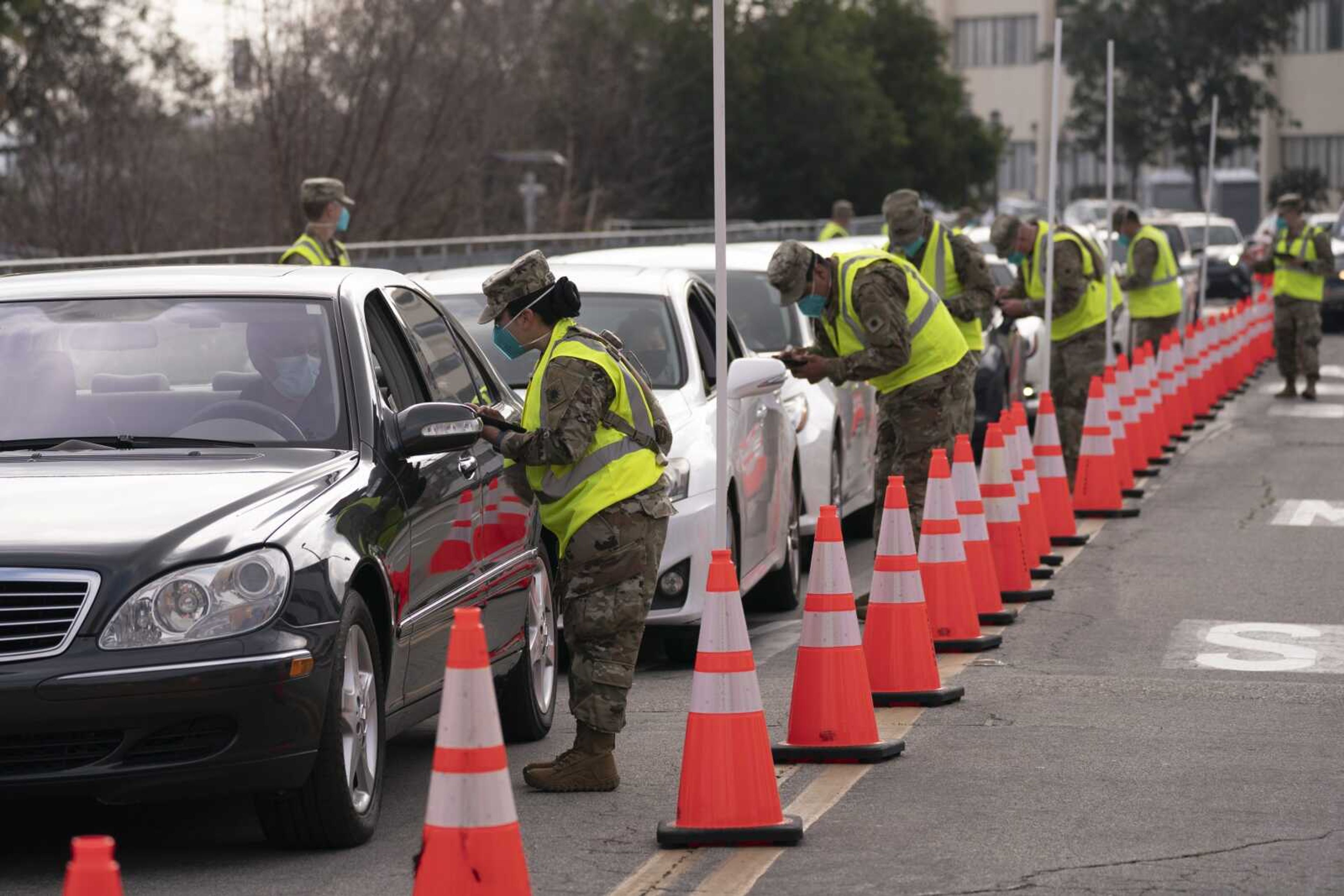 Members of the National Guard help motorists check in at a federally-run COVID-19 vaccination site Tuesday set up on the campus of California State University of Los Angeles in Los Angeles.