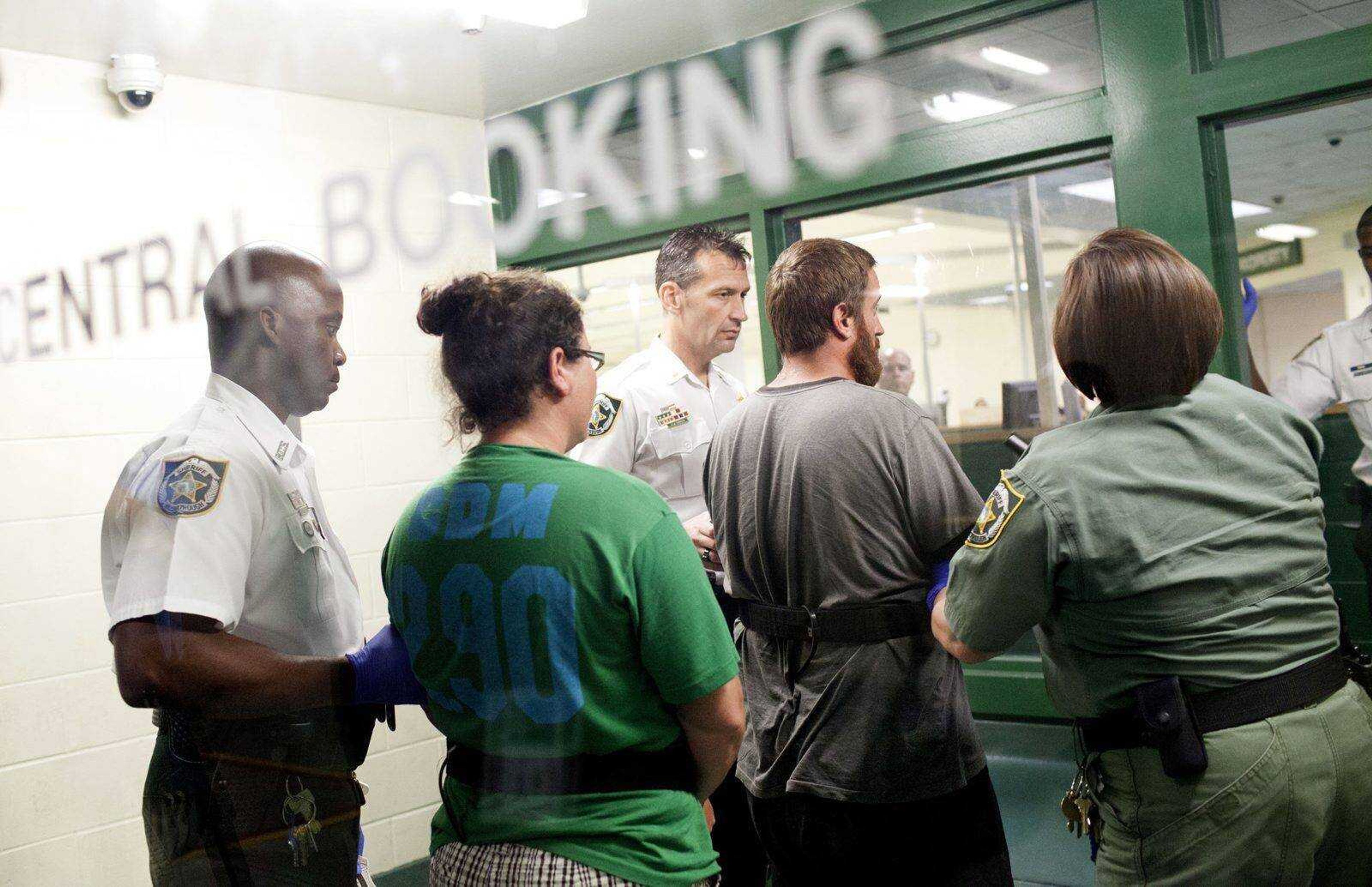 Sharyn Hakken, second from left, and Joshua Hakken, second from right, are taken into booking by Hillsborough County sheriff officers at the Orient Road Jail after being brought in from Cuba early Wednesday morning. The Hakens are accused of kidnapping their two young sons and fleeing with them to Cuba. (Austin Anthony ~ The Tampa Bay Times)