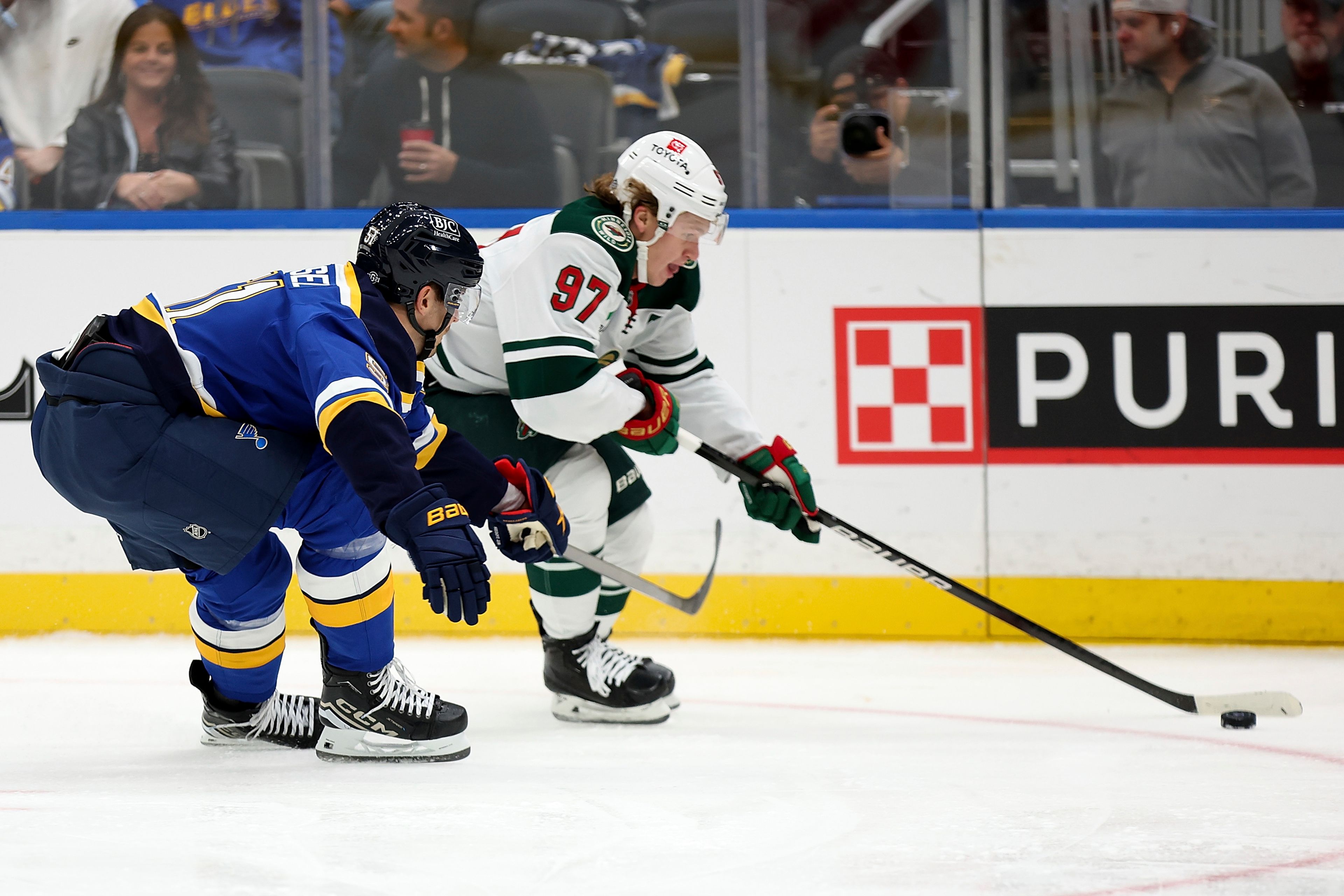 Minnesota Wild's Kirill Kaprizov (97) controls the puck while under pressure from St. Louis Blues' Matthew Kessel (51) during the first period of an NHL hockey game Tuesday, Oct. 15, 2024, in St. Louis. (AP Photo/Scott Kane)