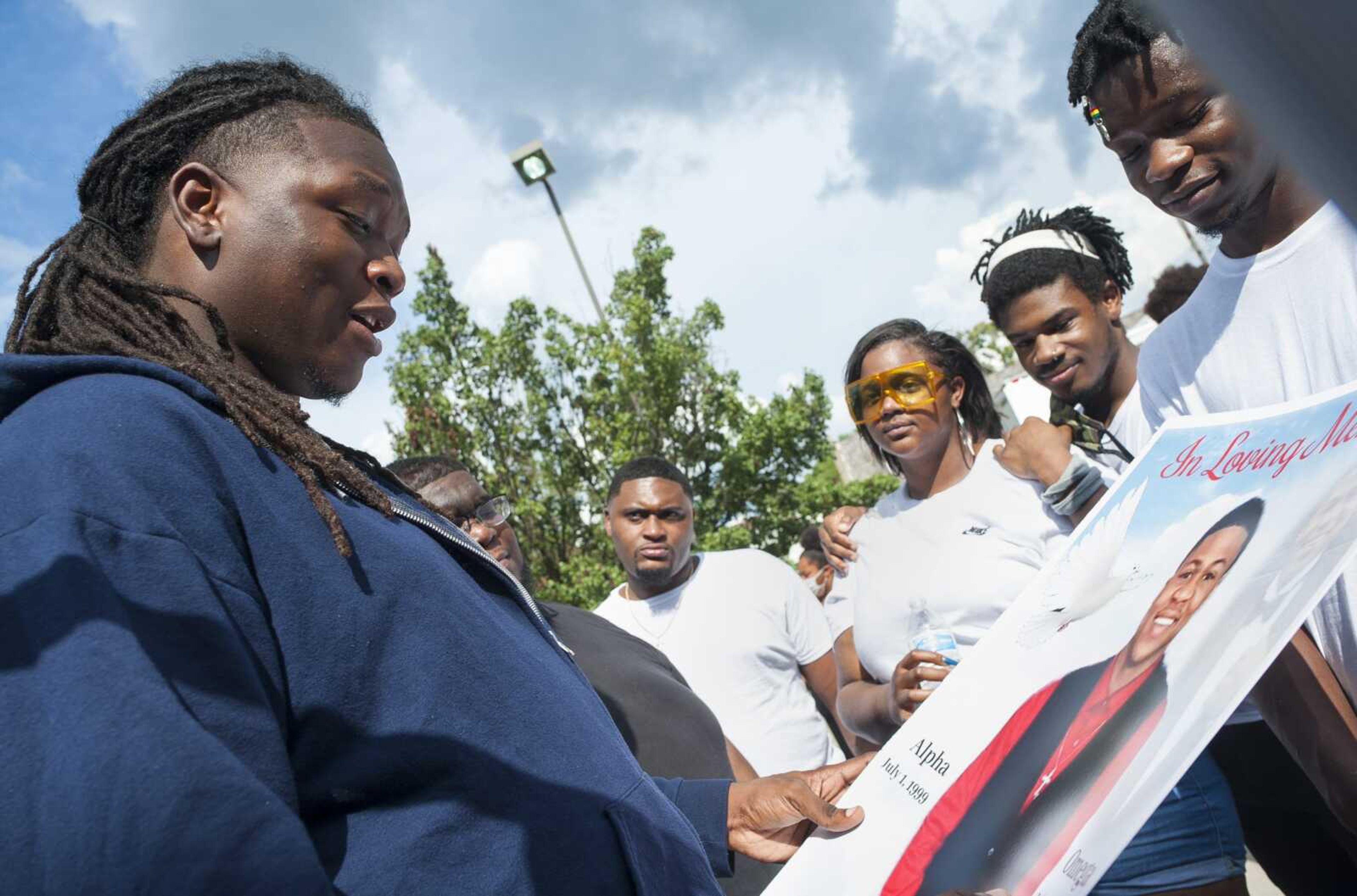 Iemeon Giles, left, holds a poster of Anthony Miller while standing with a group of Miller's friends and family after a memorial service Saturday at the Salvation Army in Cape Girardeau.