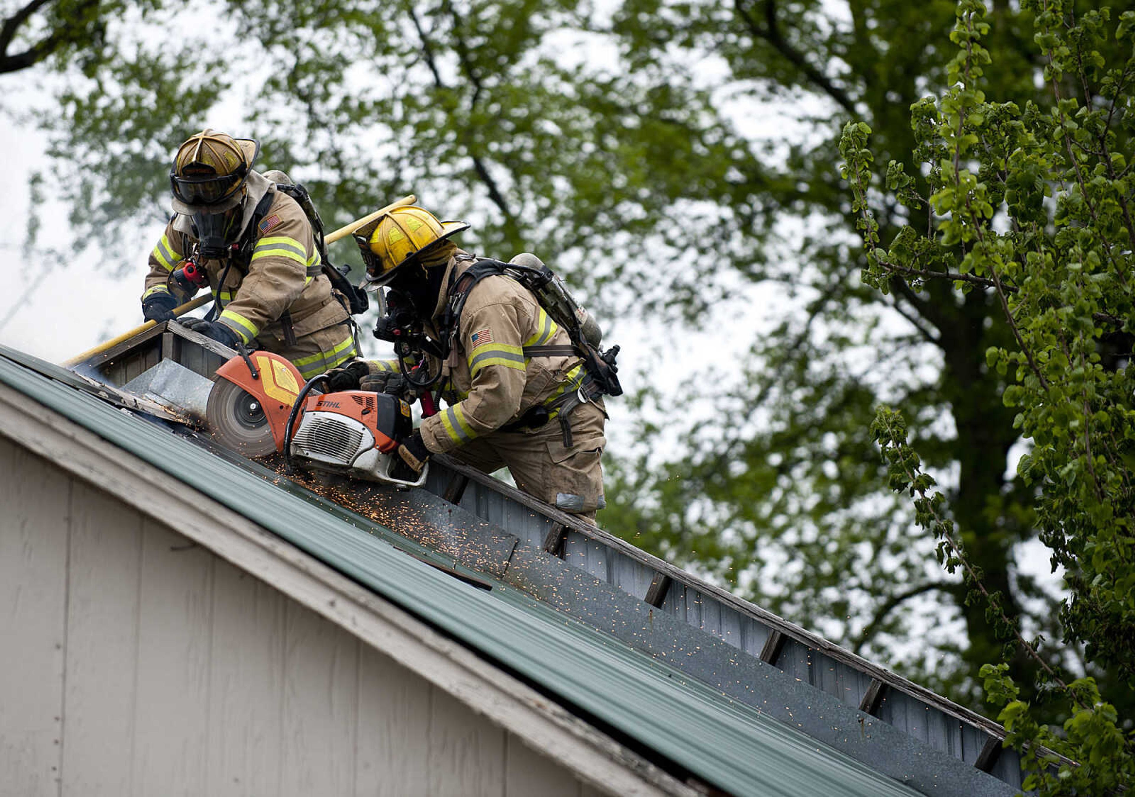 Cape Girardeau firefighters use a saw to cut through the roof as they battle a structure fire at 710 Morgan Oak  St., Tuesday, April 29, in Cape Girardeau. A Cape Girardeau Police officer saw the fire and called it in at 1:16 p.m. The building contained two apartments that were home to five people, though no one was home at the time of the fire. The cause of the fire is under investigation.