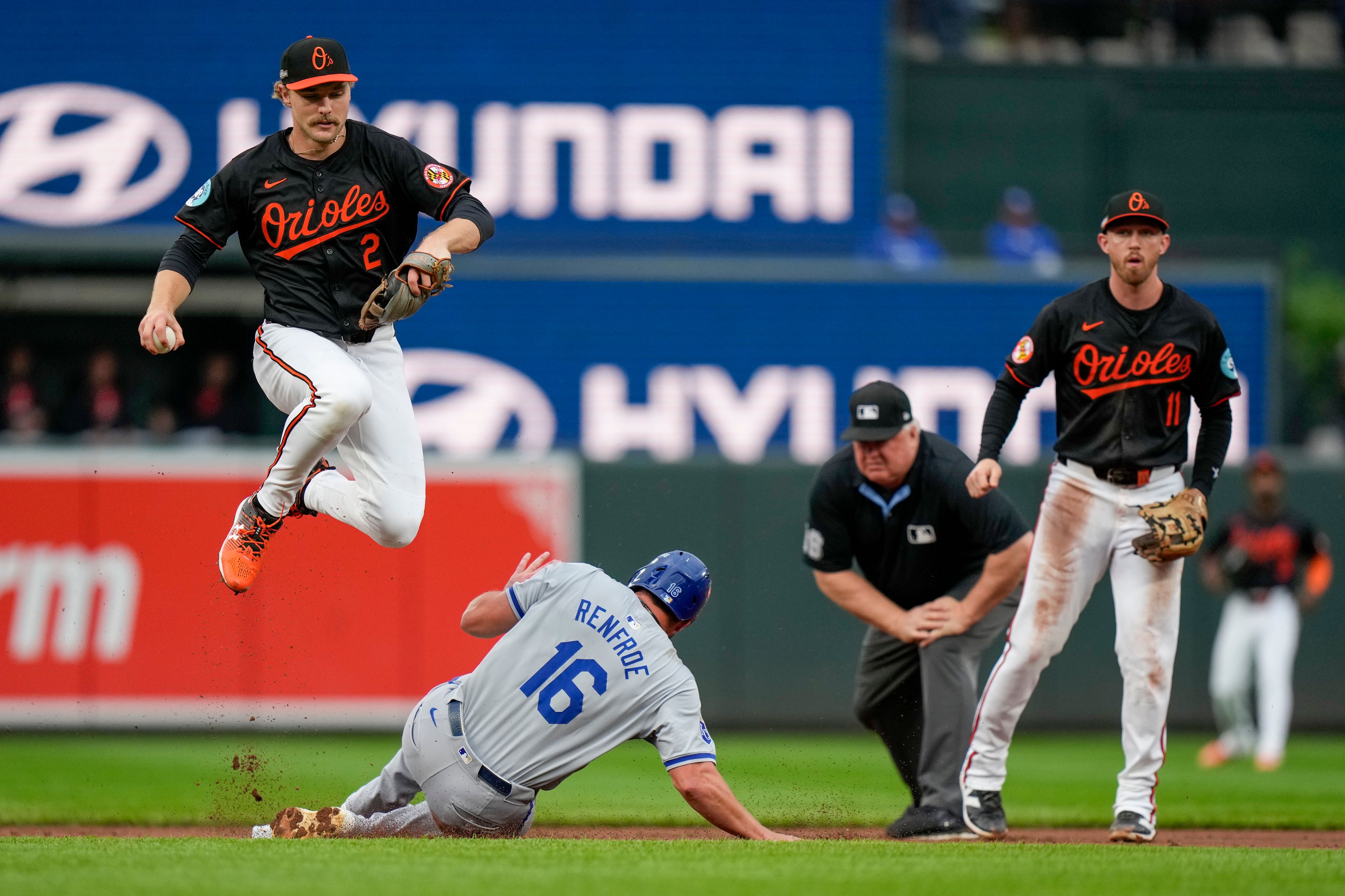 Baltimore Orioles shortstop Gunnar Henderson, top left, leaps to avoid the slide of Kansas City Royals' Hunter Renfroe (16) after forcing him out on a ground ball hit by Kyle Isbel during the second inning in Game 2 of an AL Wild Card Series baseball game, Wednesday, Oct. 2, 2024 in Baltimore. Second base umpire Bill Miller, second from right, and third base Jordan Westburg (11) look on. (AP Photo/Stephanie Scarbrough)