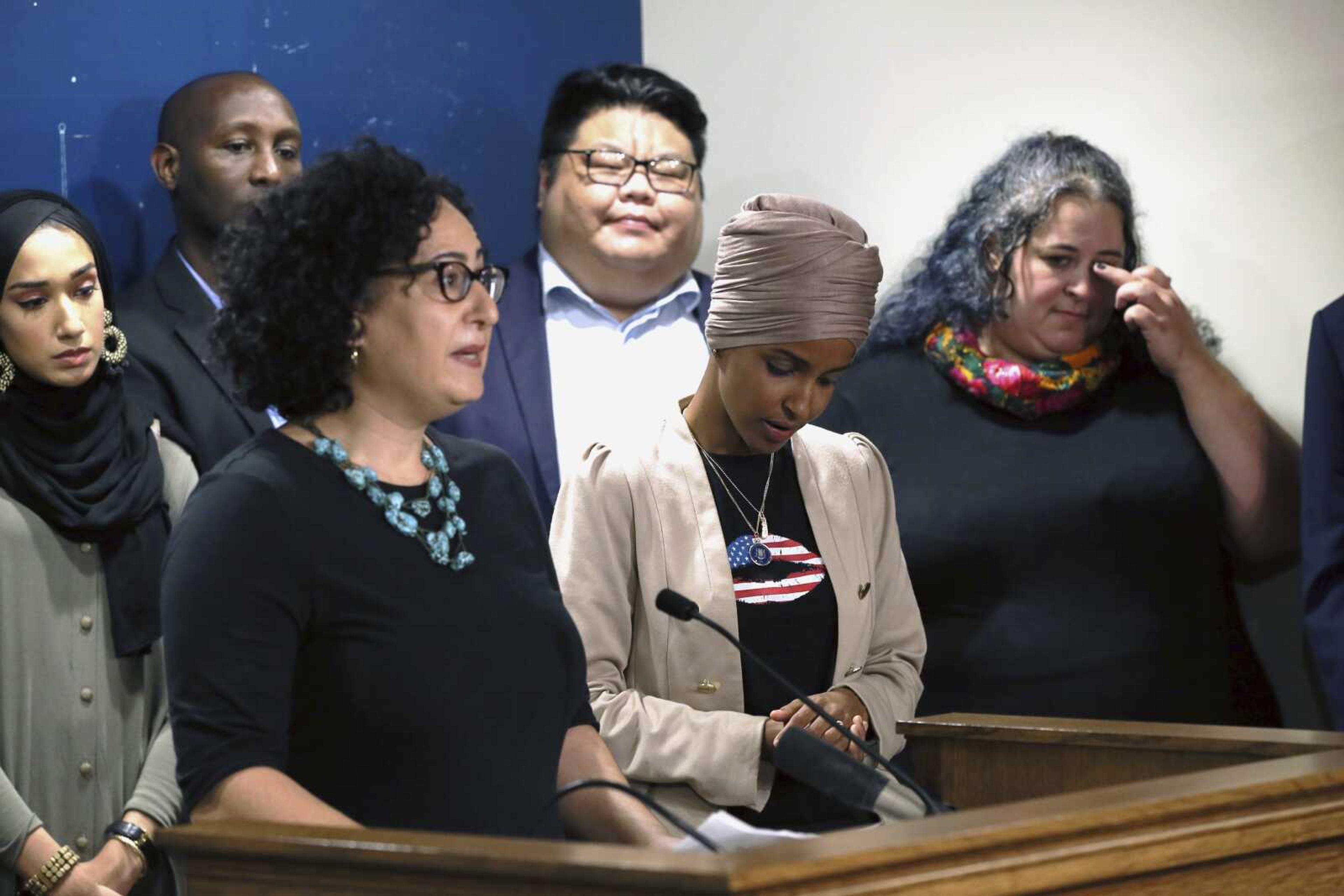 Rep. Ilhan Omar, D-Minn., center, listens as Lana Barkawi, left, talks about Israel travel restrictions she has faced during a news conference Monday, Aug. 19, 2019 at the State Capitol in St. Paul, Minn., held by Omar and Rep. Rashida Tlaib, D-Mich., who talked about Israel's refusal to allow them to visit the country. Barkawi is a Palestinian-American. Others who have faced travel restrictions are shown during the news conference. (AP Photo/Jim Mone)