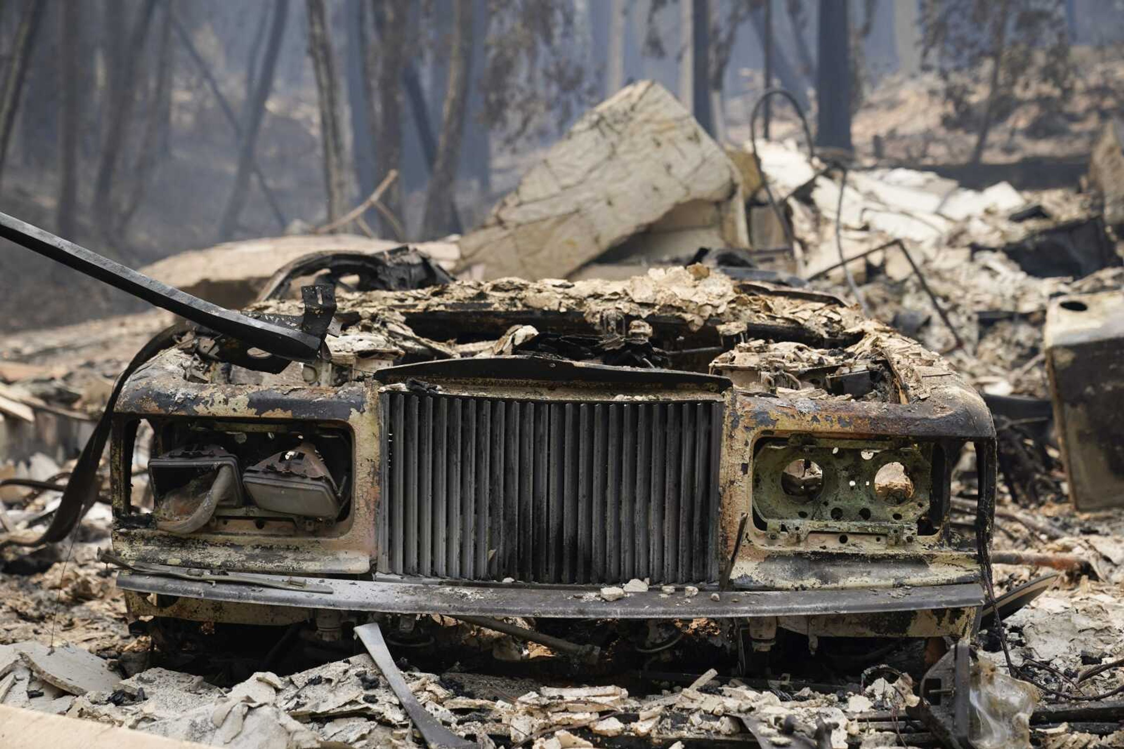 A charred vehicle is parked in front of a home after the CZU Lightning Complex Fire went through Sunday in Boulder Creek, California.