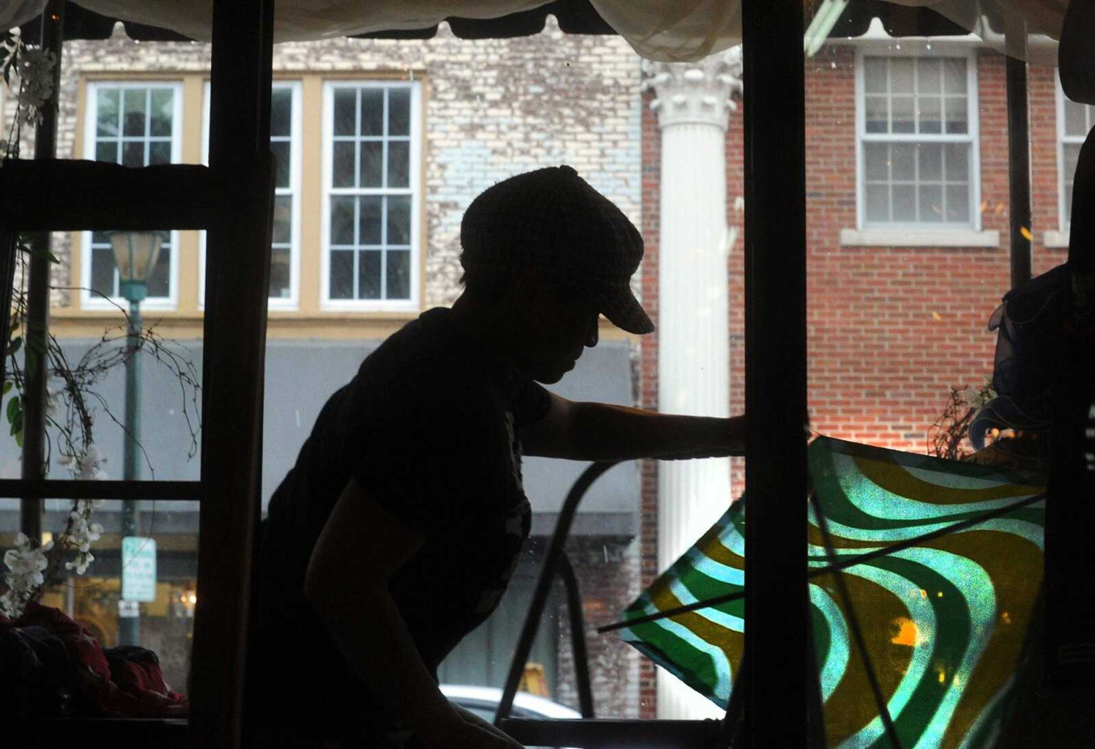 Judith Golightly adds a vintage kite to her window display in front of her shop, Judith's Antiques, on Wednesday in downtown Cape Girardeau. Golightly changes her window display each week. (Laura Simon)