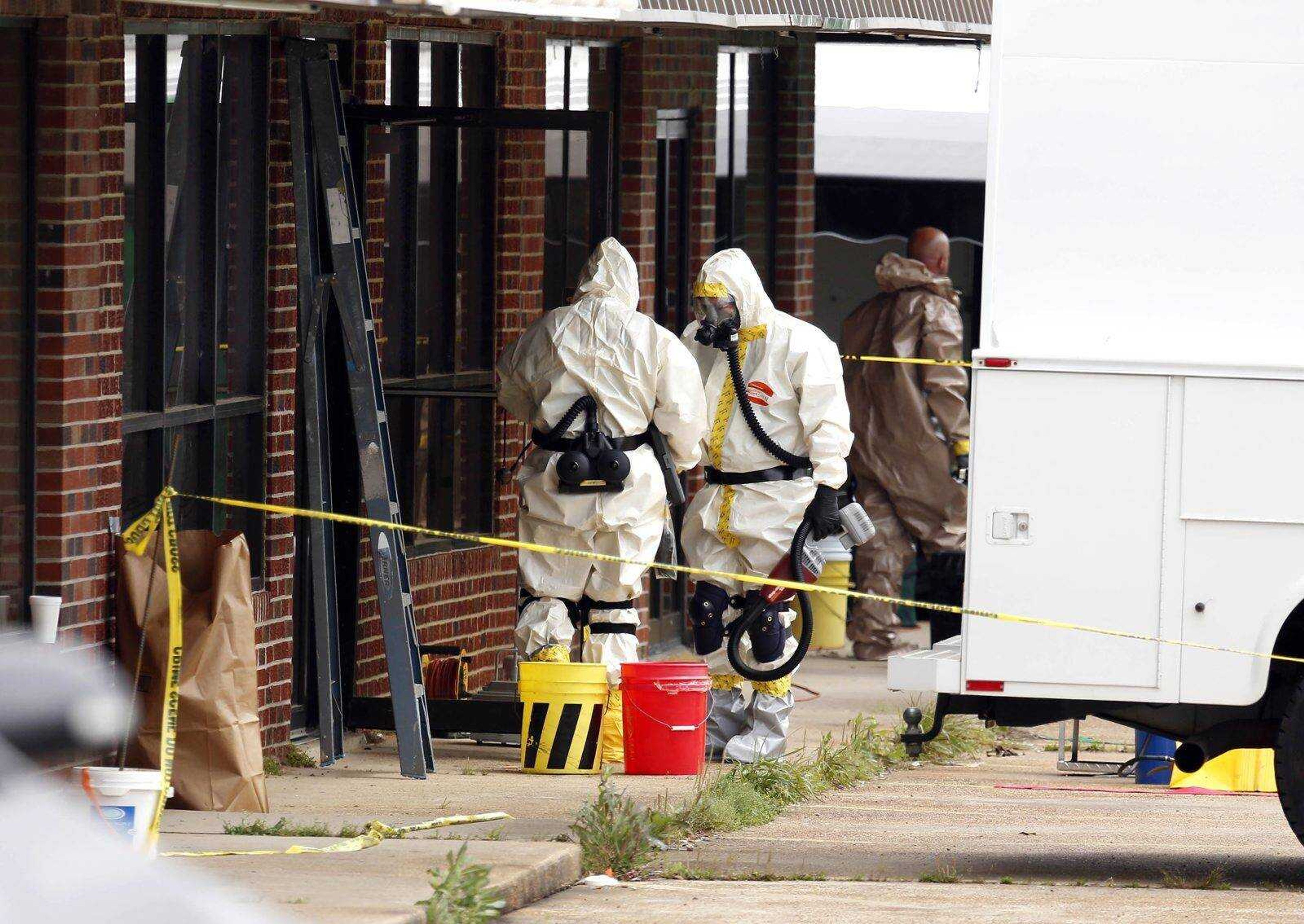 Federal authorities, some in hazmat suits, walk outside the staging area as they search at a small retail space where neighboring business owners said Everett Dutschke used to operate a martial arts studio, in connection with the recent ricin attacks, Wednesday, April 24, 2013 in Tupelo, Miss. No charges have been filed against Dutschke and he hasn&#180;t been arrested. (AP Photo/Rogelio V. Solis)