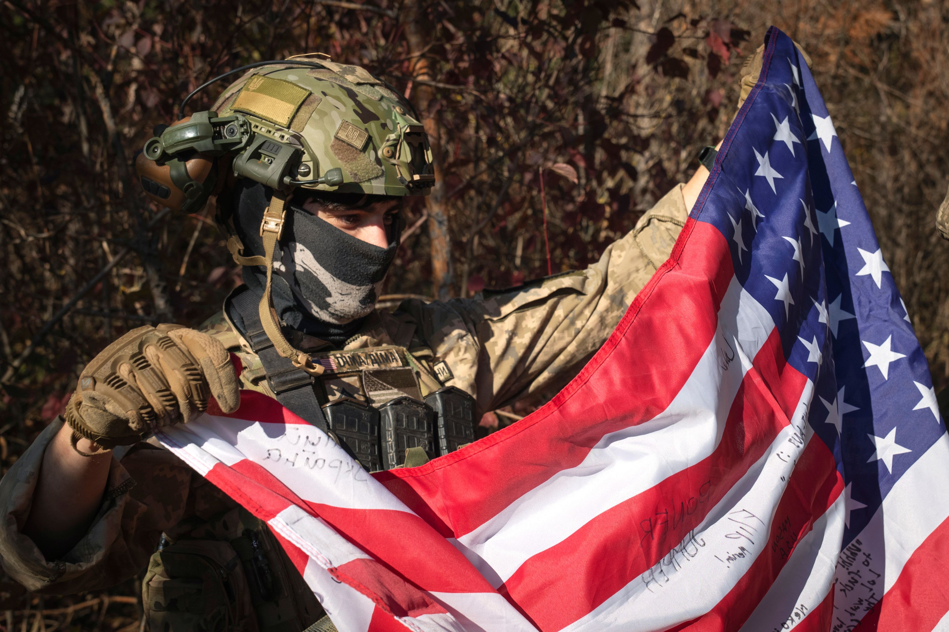 FILE - A 25-year-old volunteer fighter identified only as Dima, who is from the U.S. state of Texas and serves with the 23rd rifle battalion of Ukraine’s armed forces, holds a U.S. flag near the front line in the Kharkiv region of Ukraine, on Oct. 26, 2024. (AP Photo/Efrem Lukatsky, File)