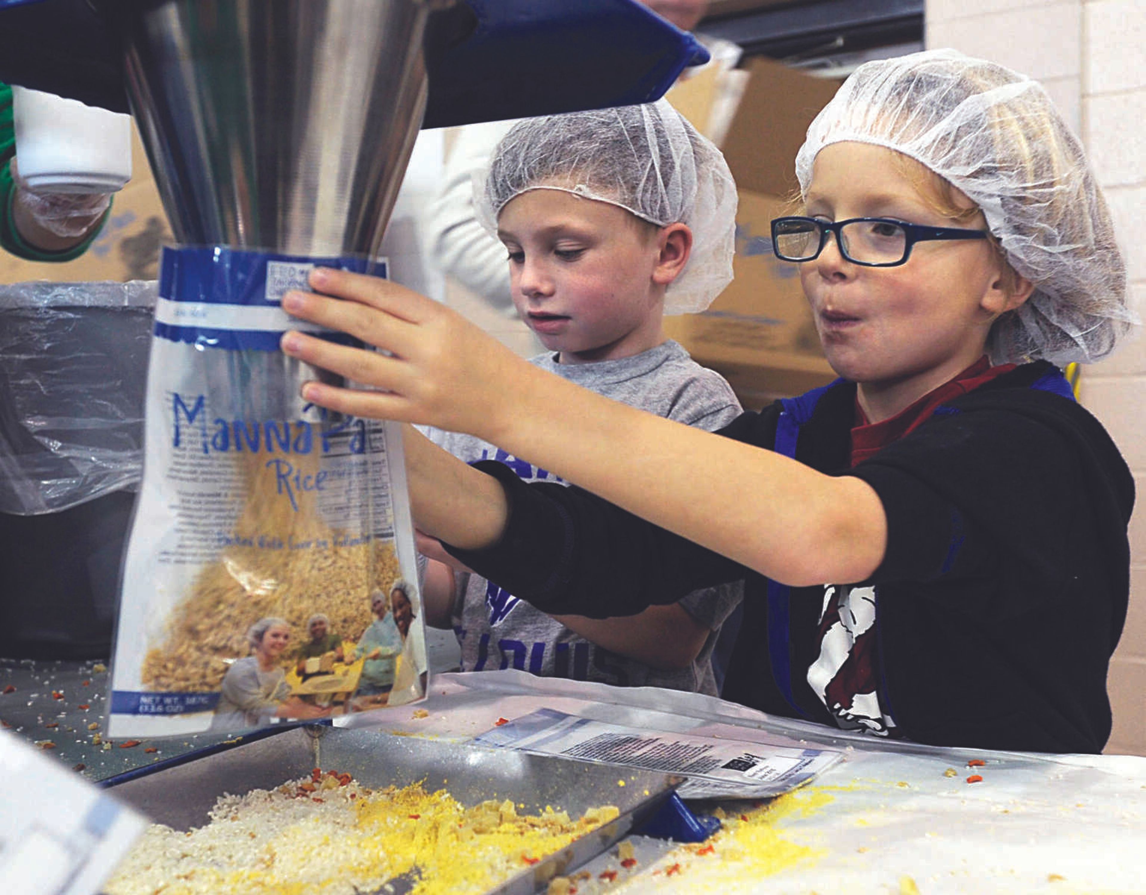 By line:Spencer Engelhardt, left, and Max Heuring assist with filling MannaPack rice bags at the Feed My Starving Children MobilePack event Dec. 7, 2014, at the Osage Centre in Cape Girardeau. (Fred Lynch)