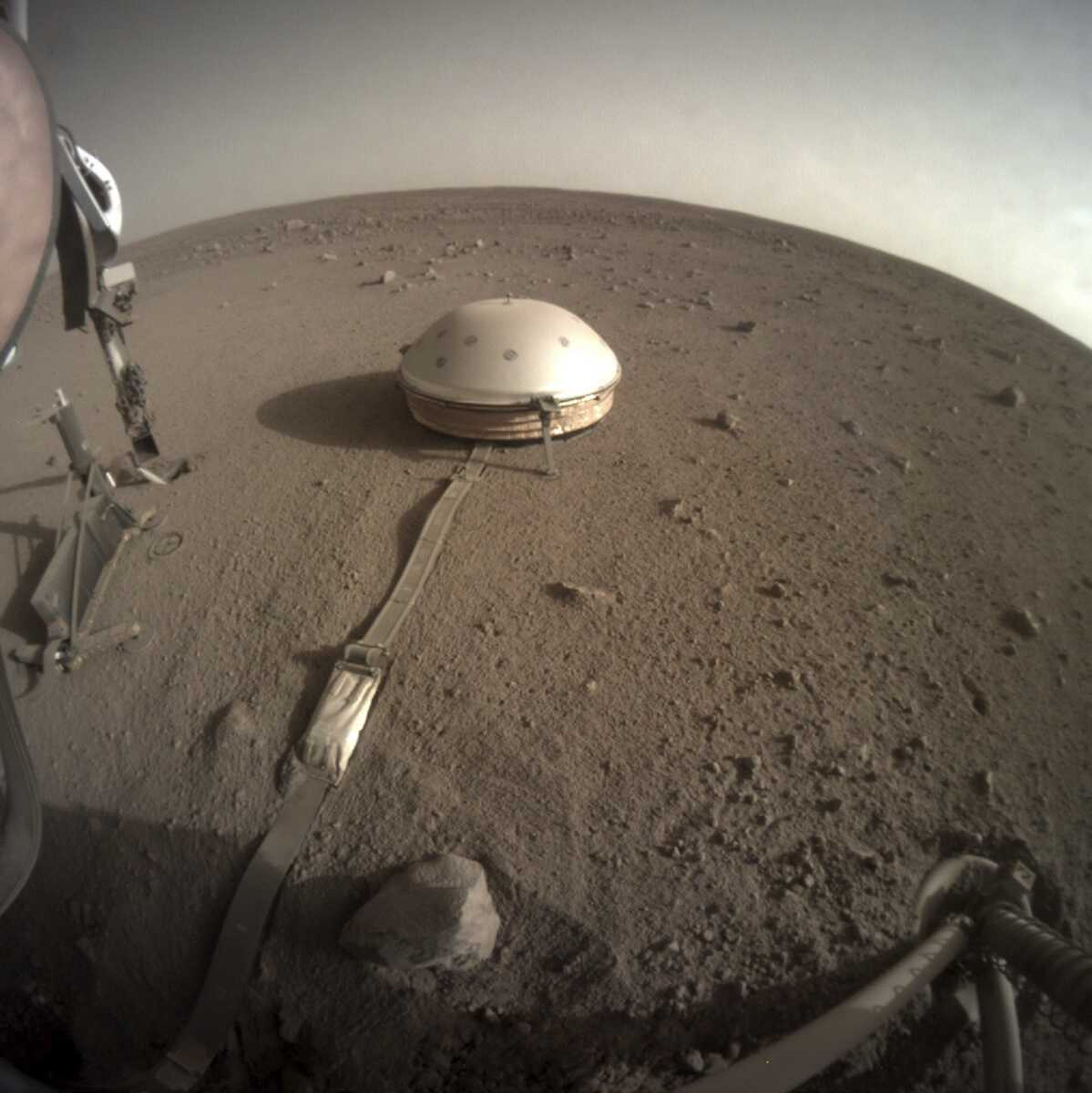 The InSight lander's dome-covered seismometer, known as SEIS, is seen Feb. 18 on Mars. On Monday, scientists reported that the spacecraft has detected hundreds of quakes and even aftershocks regularly jolting the red planet.