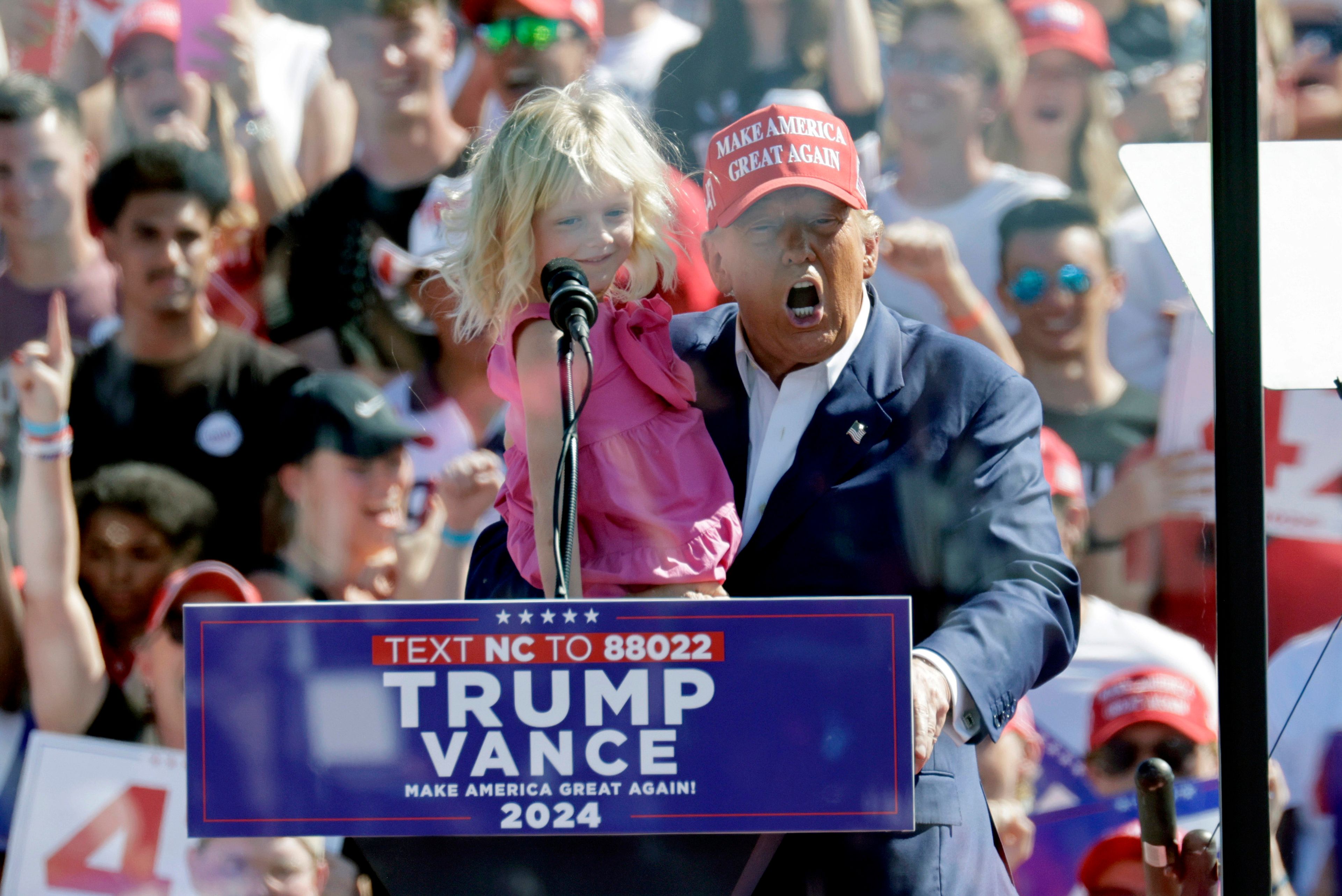 Republican presidential nominee former President Donald Trump holds his granddaughter Carolina Trump as he speaks at a campaign event at Wilmington International Airport in Wilmington, N.C., Saturday, Sept. 21, 2024. (AP Photo/Chris Seward)