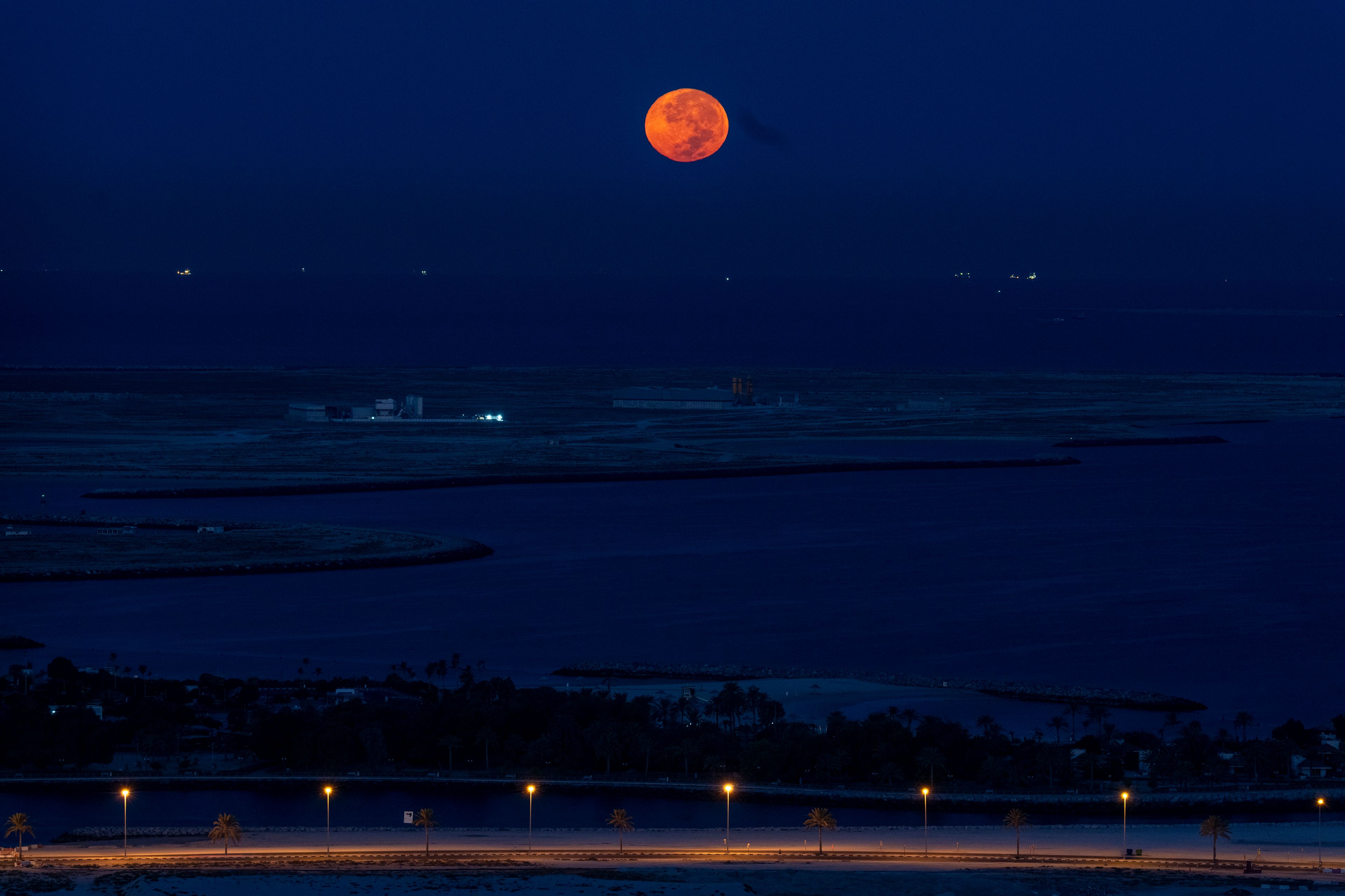 A supermoon sets over the Persian Gulf as dawn breaks in Dubai, United Arab Emirates, Thursday, Oct. 17, 2024. (AP Photo/Altaf Qadri)