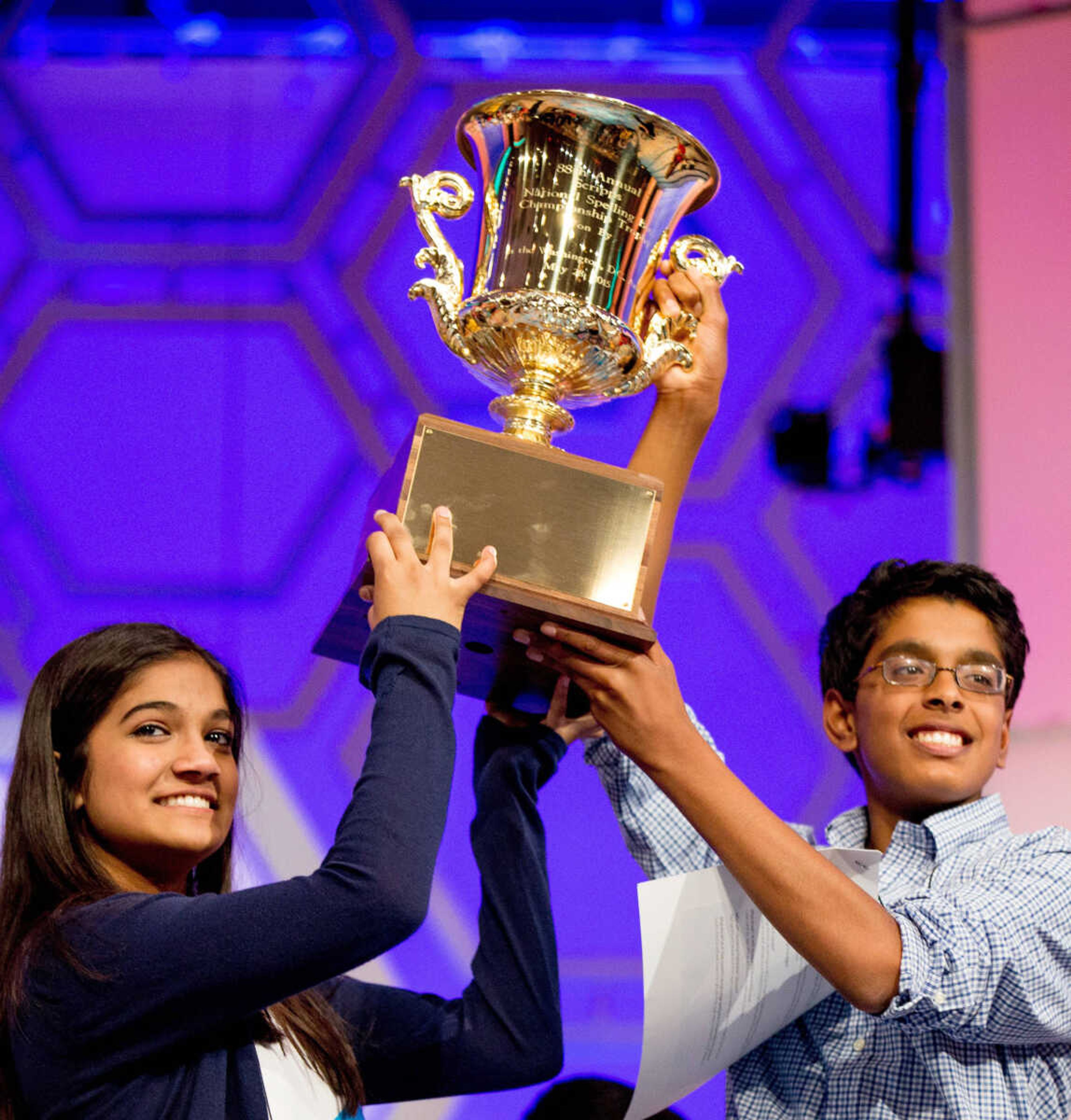 Vanya Shivashankar, 13, left, of Olathe, Kansas, and Gokul Venkatachalam, 14, of Chesterfield, Missouri, hold up the trophy as co-champions after winning the finals of the Scripps National Spelling Bee on Thursday in Oxon Hill, Maryland. (Andrew Harnik ~ Associated Press)