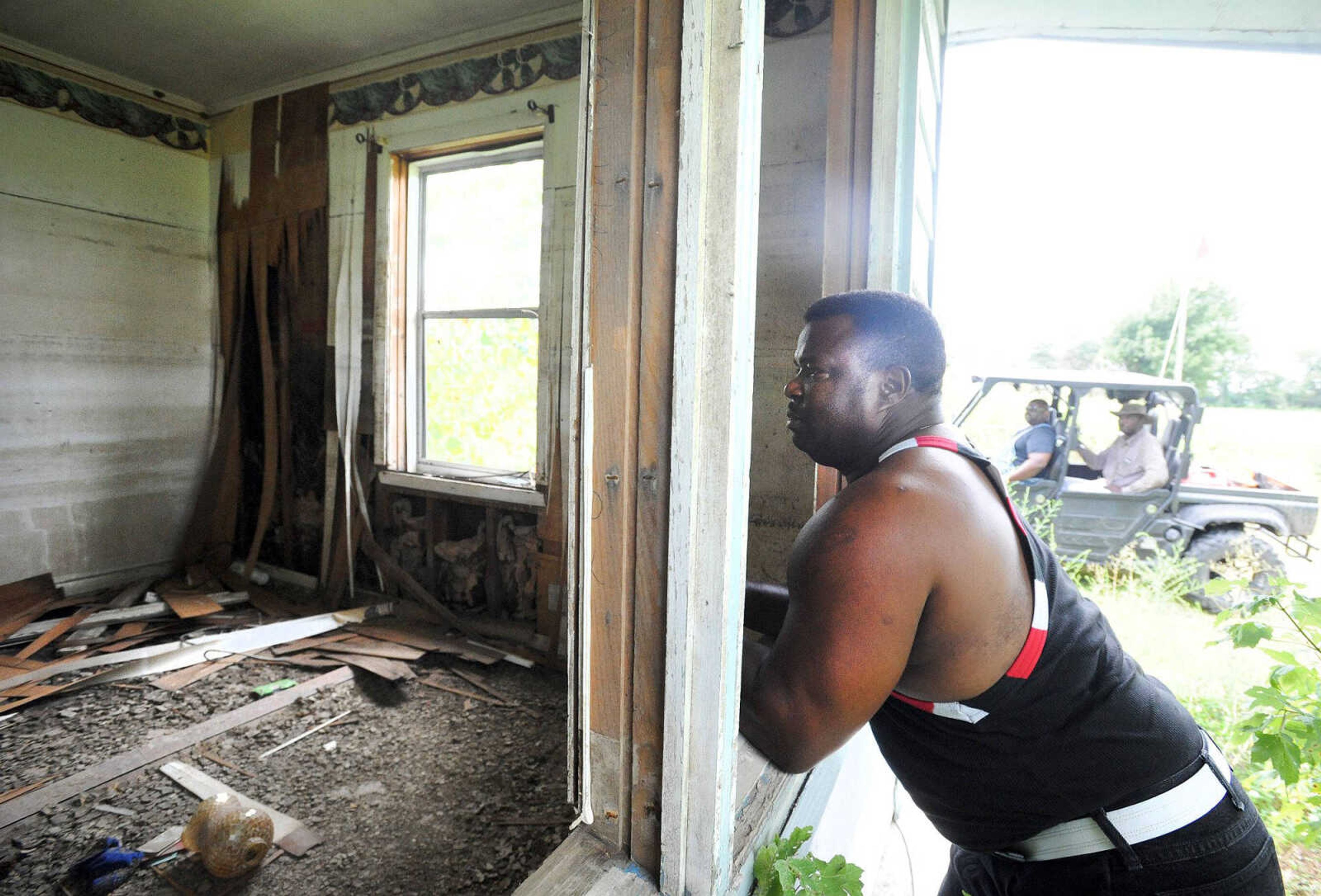 Reginald Robinson looks inside his cousin's vacant Pinhook, Missouri, home Thursday. Pinhook was ravaged by floodwater in 2011 when the U.S. Army Corps of Engineers breached the Birds Point Levee in Mississippi County. Robinson drove from his current home in Wisconsin to be with his family as demolition began Thursday on the remaining structures in Pinhook. Robinson's brother, David, and family friend, Leonard Gallion, are seen in the background. (Laura Simon)