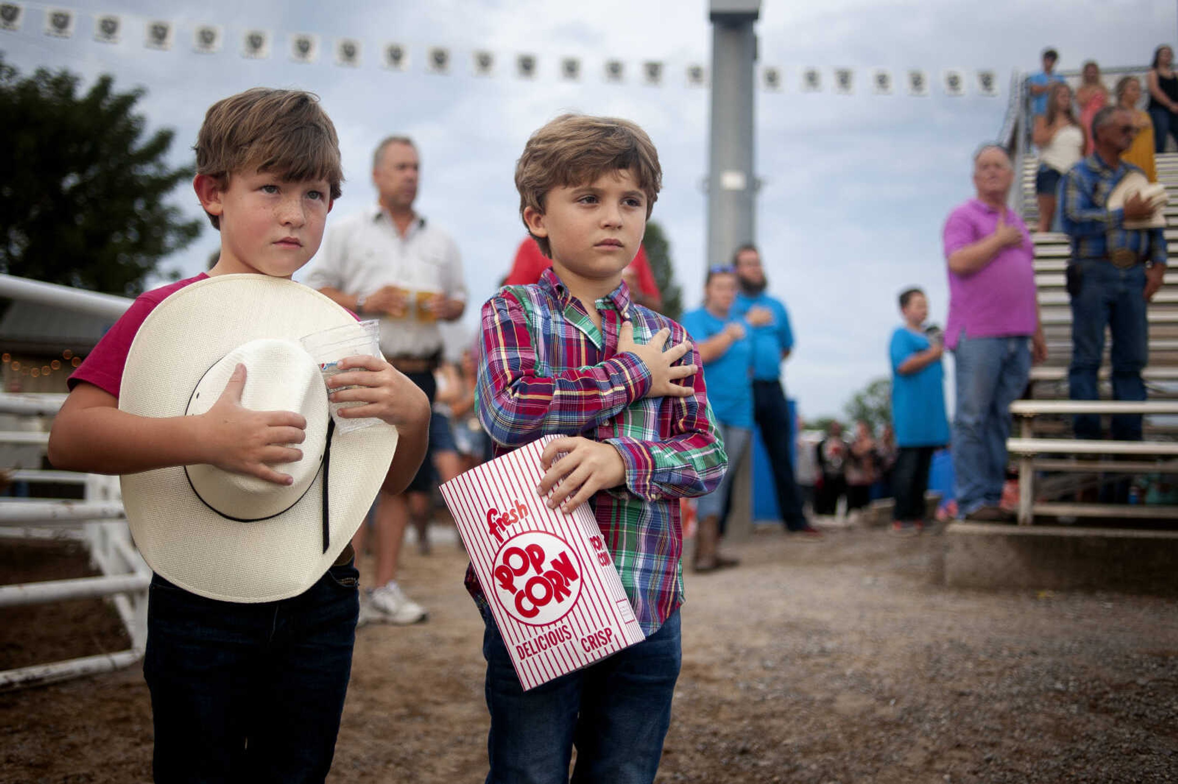 John-Ross Williams, 6, left, and Rylan Ryan, 7, both of Sikeston, Missouri, stand with the rest of the crowd for the playing of the national anthem at the start of opening night of the Sikeston Jaycee Bootheel Rodeo on Wednesday, Aug. 7, 2019, in Sikeston.