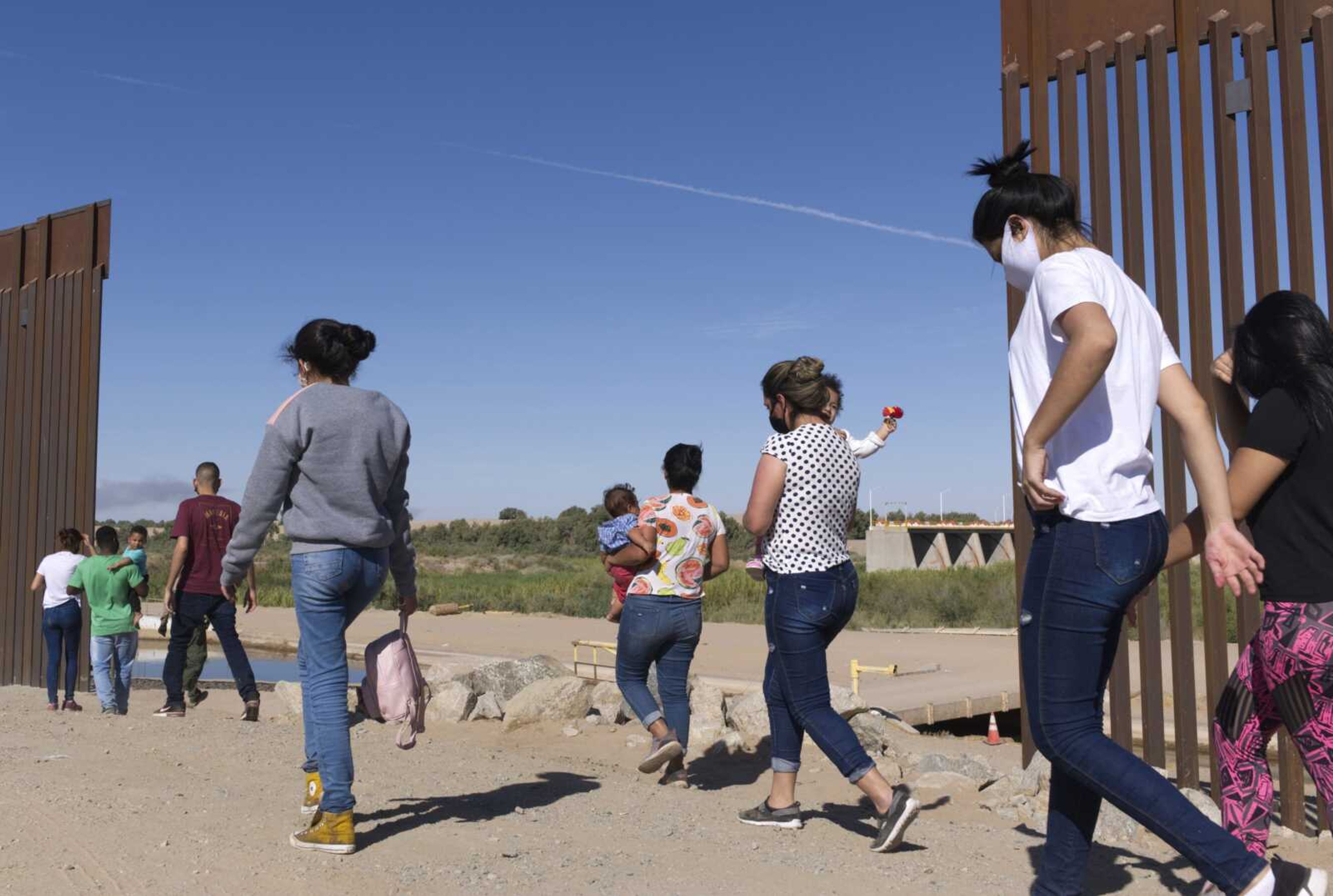 A group of Brazilian migrants make their way around a gap in the U.S.-Mexico border June 8 in Yuma, Arizona, seeking asylum in the U.S. after crossing over from Mexico. Two Republican border-state governors who are investing billions of dollars on immigration enforcement and hours at the podium blasting the Biden administration policies have found two unlikely allies: Democratic mayors Muriel Bowser of Washington, D.C., and Eric Adams of New York. The mayors' recent overtures for federal aid is a response to Texas and Arizona busing migrants away from the border, a months-old practice that has been long on political theater and short on practical impact.